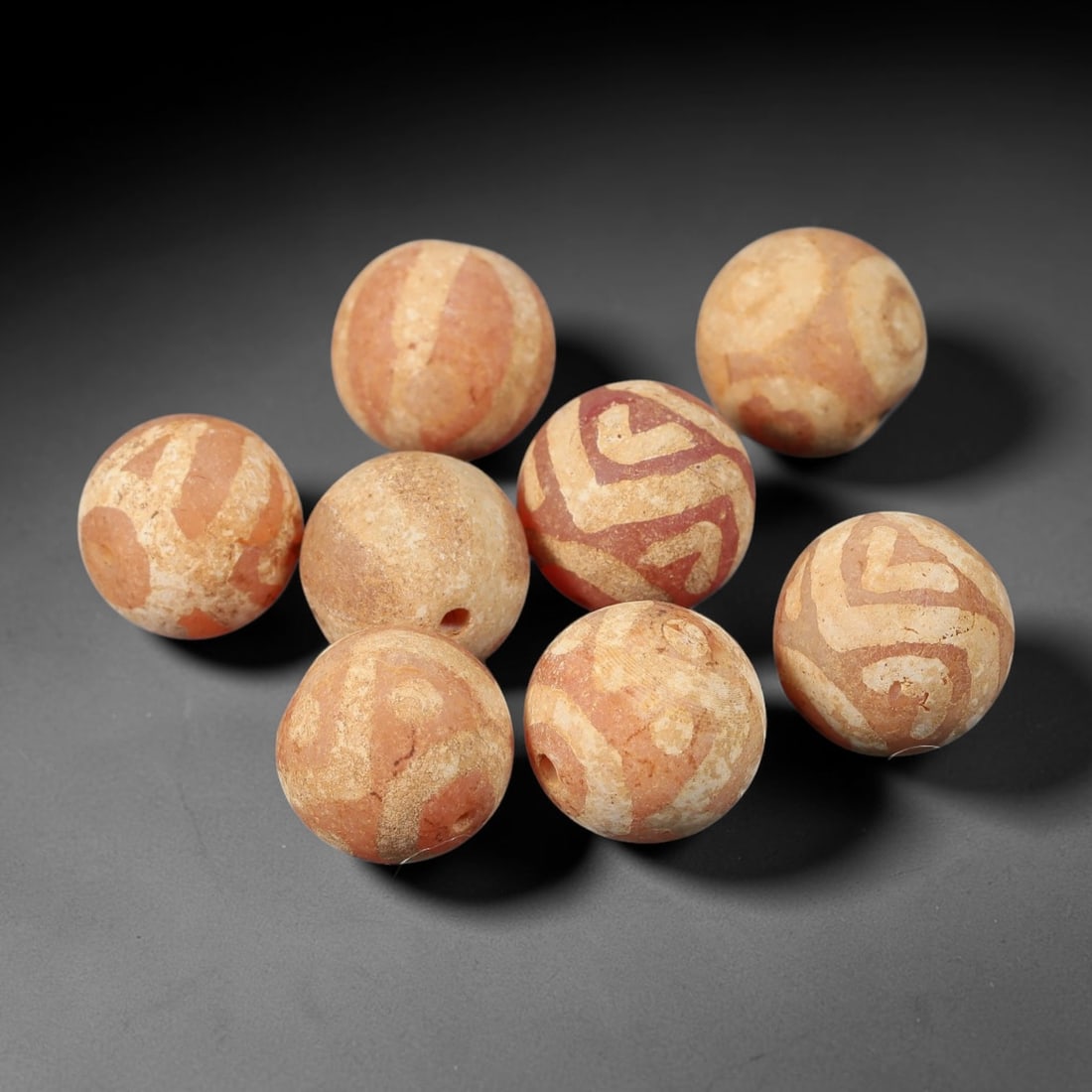 Ancient Carnelian Etched Beads - Gandhara Amulet Set, 43BE: Set of eight spherical beads crafted from carnelian, each decorated with etched geometric motifs in a pale white pigment, characteristic of Gandharan decorative traditions. The beads retain a well-dev