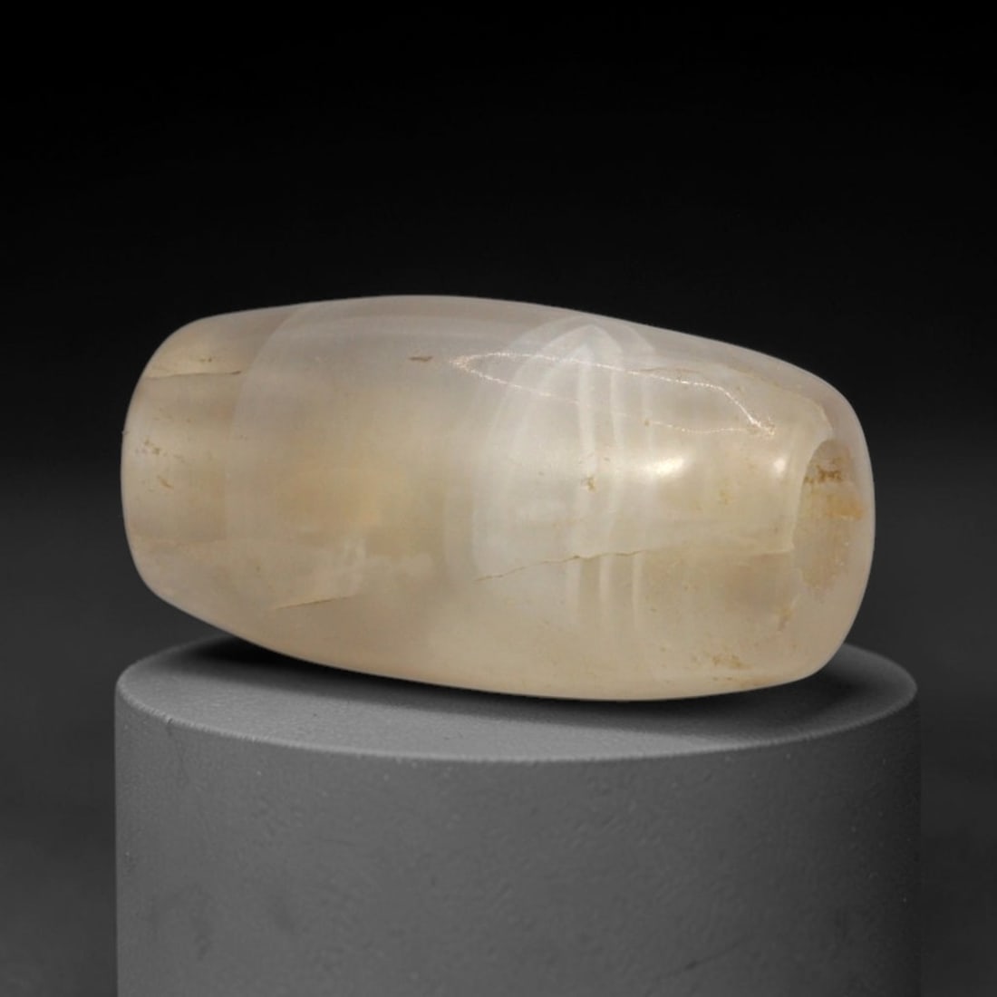 Ancient Agate Bead - Western Asiatic Silk Road Pendant, 2XY: This bead is carved from translucent agate with natural internal fissures and subtle surface patination consistent with ancient wear. It is fashioned in a barrel shape with rounded ends and drilled lo
