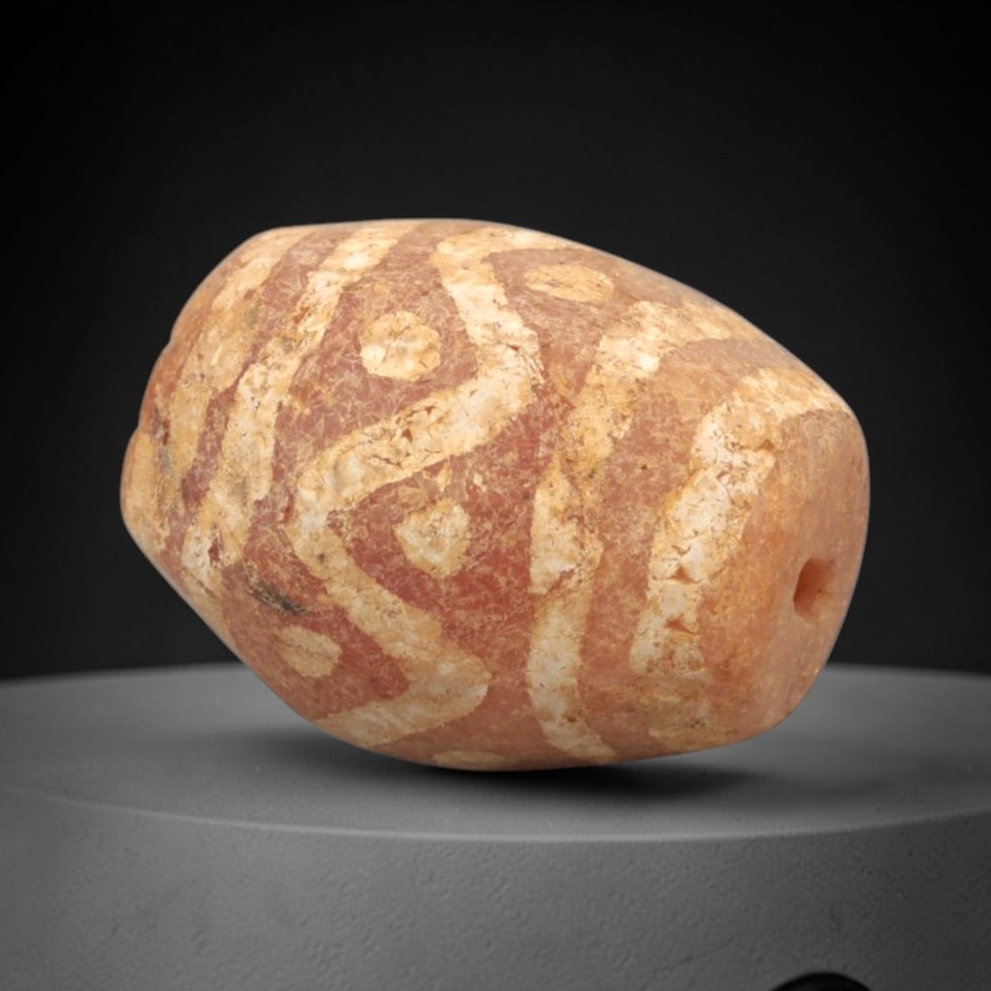 Ancient Carnelian Etched Bead - Gandhara Amulet, 48XY: Carved from carnelian, the bead is fashioned in an elongated barrel form with a lateral drilled suspension hole for wear. The surface is decorated with an intricate white-etched pattern of interlockin