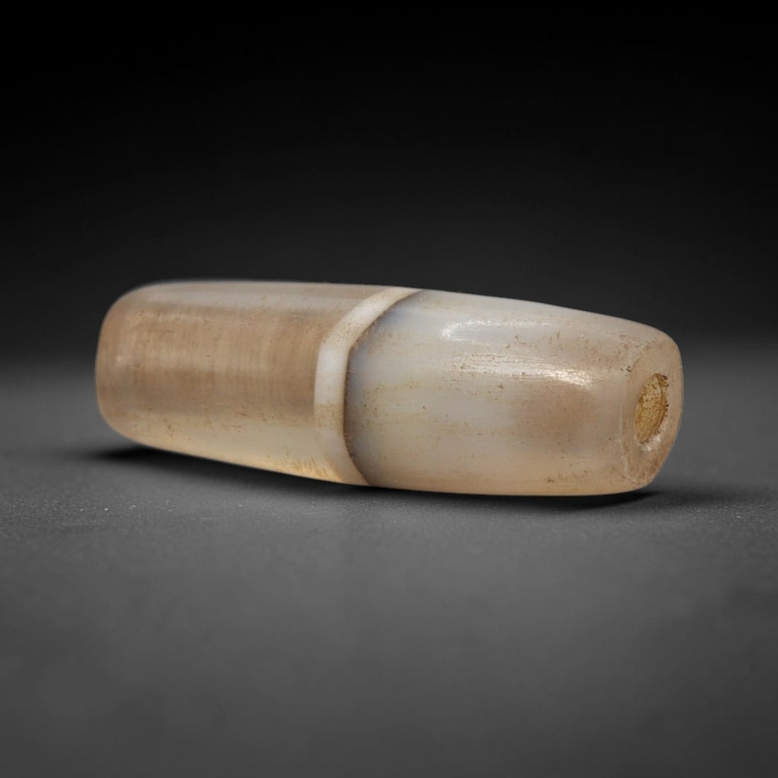 Ancient Agate Bead - Indus Valley Asiatic Pendant, 1XY: This bead is fashioned from banded agate with characteristic mottled inclusions typical of Western Asiatic lapidary traditions. It is cylindrical in form with rounded ends and drilled longitudinally f