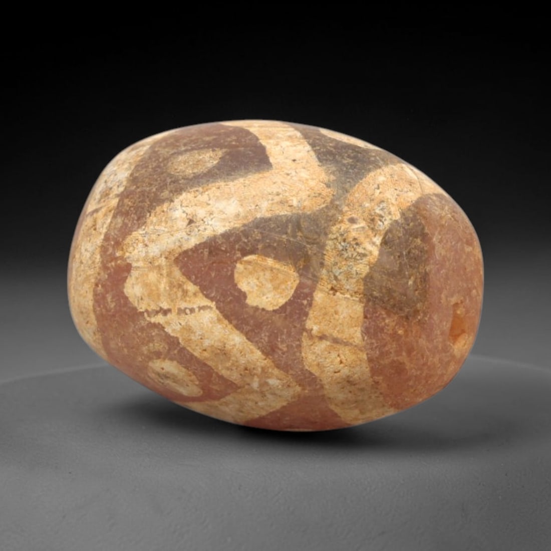Ancient Carnelian Etched Bead - Gandhara Amulet, 45XY: Carved from carnelian, the bead is fashioned in an oval barrel form with a lateral drilled suspension hole for wear. The surface is adorned with intricate white-etched geometric motifs, including inte