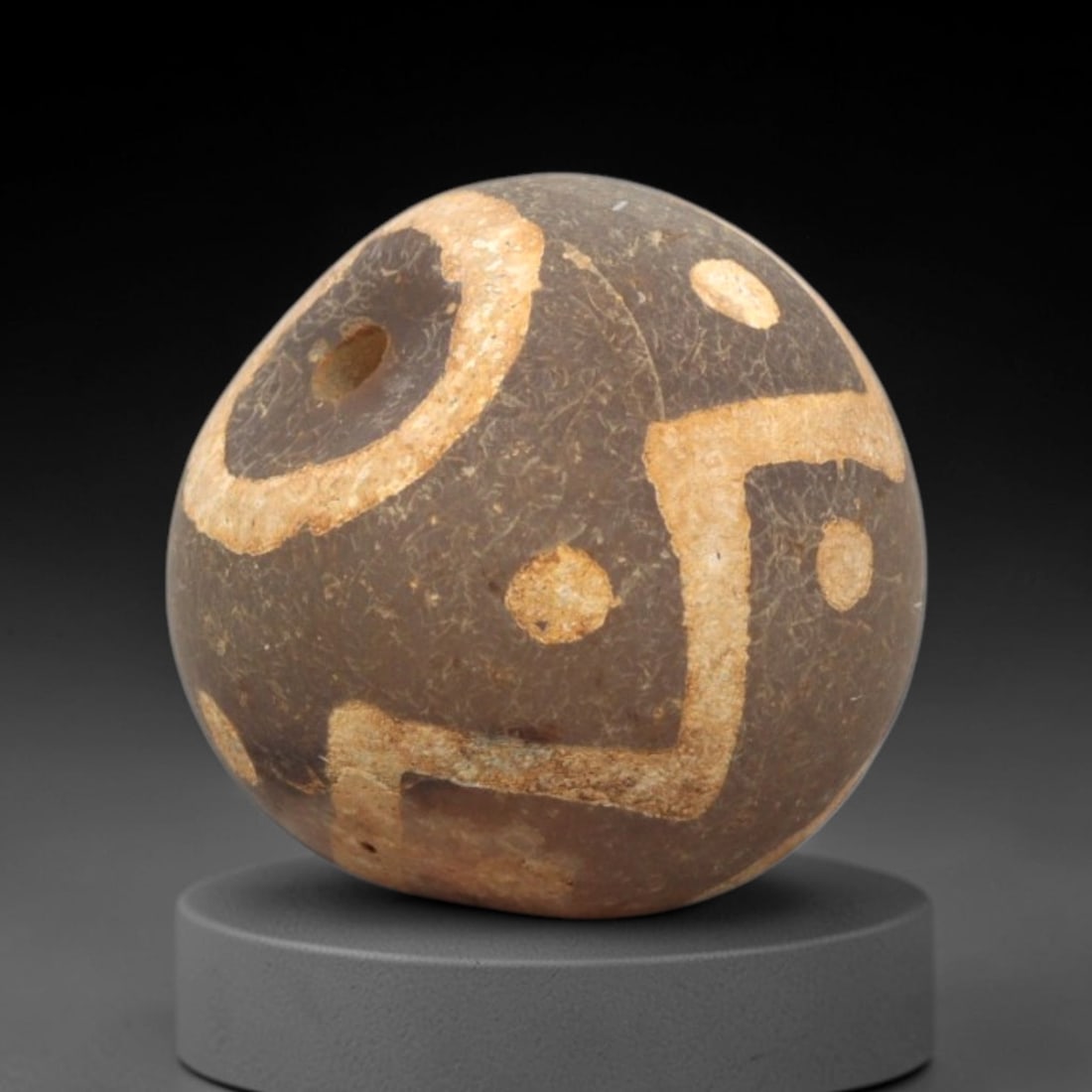 Ancient Carnelian Etched Bead - Gandhara Spherical Bead, 37XY: The bead is carved from carnelian, a semi-precious chalcedony, with a spherical form and a laterally drilled suspension hole. Its surface features an etched white geometric pattern of circular motifs,