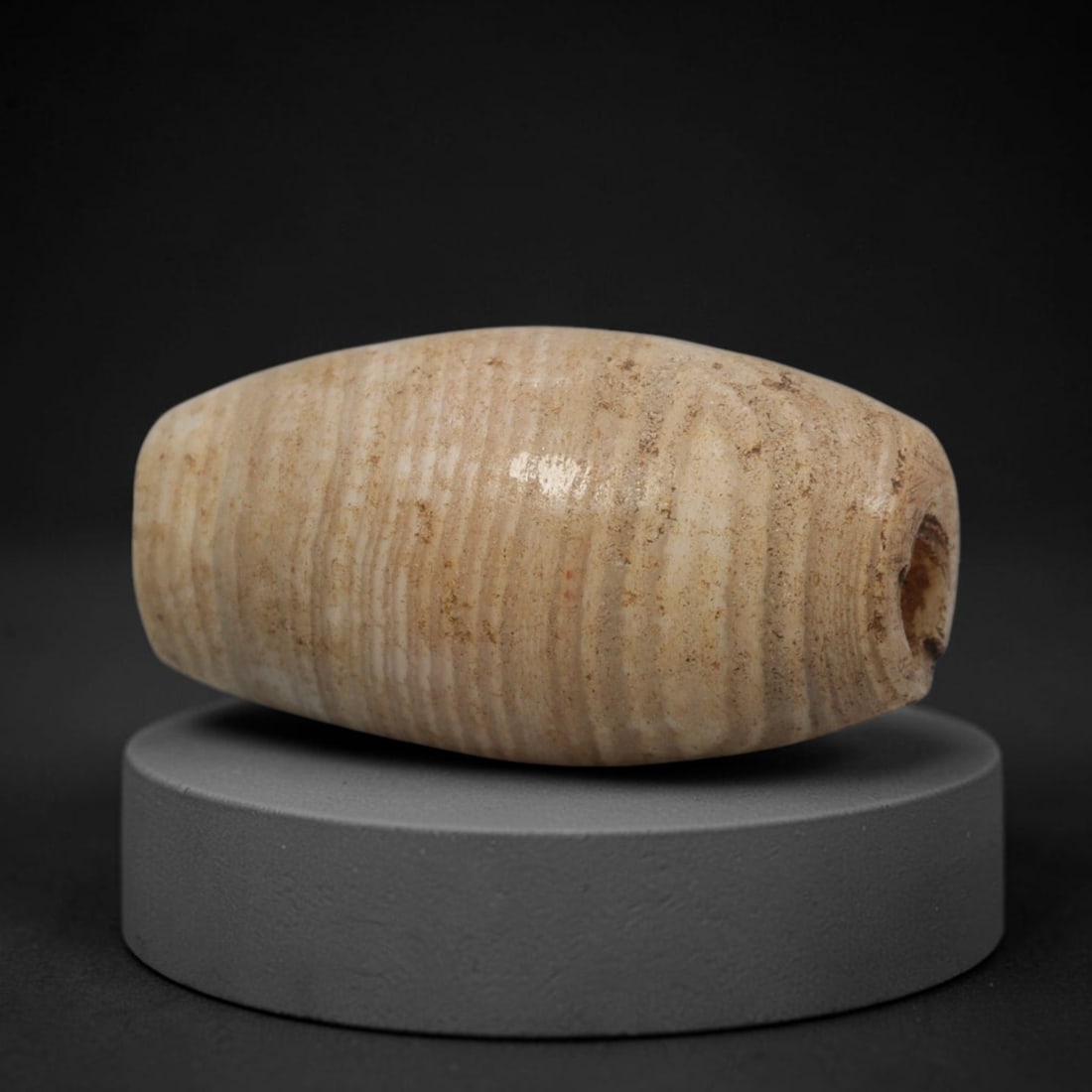 Ancient Agate Bead - Bactrian Banded Tubular Bead, 65XW: This bead is fashioned from banded agate with layers of creamy-white and warm tan mineralization, shaped into a refined tubular form with a precisely centered axial drill hole, characteristic of ancie