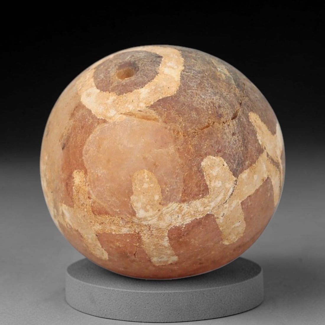 Ancient Carnelian Etched Bead - Gandhara Archaeological Find, 13BE: Carved from natural carnelian, the bead is spherical in form, featuring white etched geometric motifs across its surface. A lateral drilled suspension hole is present, characteristic of Gandharan bead