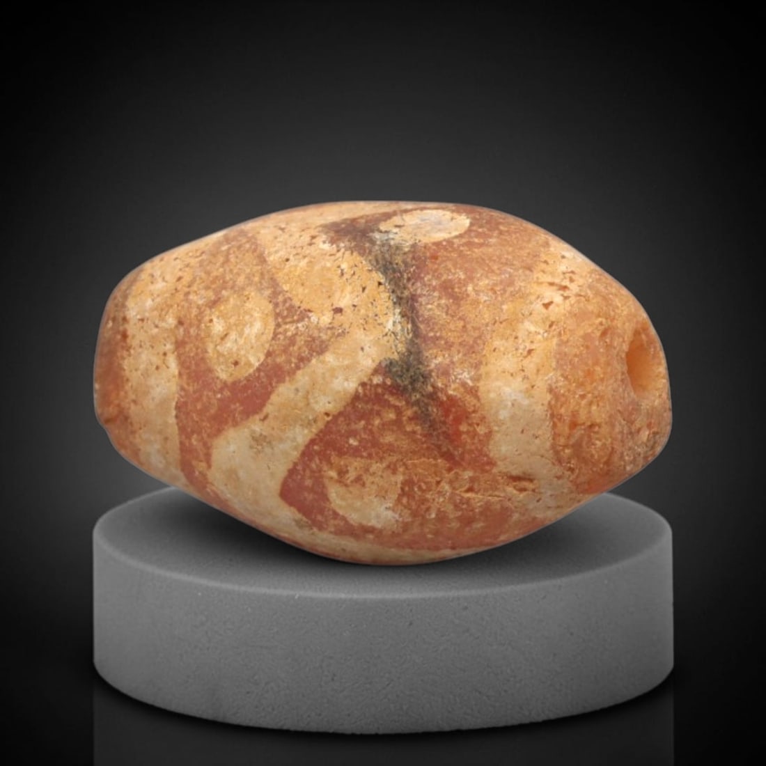 Ancient Carnelian Etched Bead - Gandhara Amulet, 39XY: Carved from carnelian, the bead is fashioned in an oval barrel form with a lateral drilled suspension hole for wear. The surface is decorated with a white-etched geometric pattern of curvilinear bands