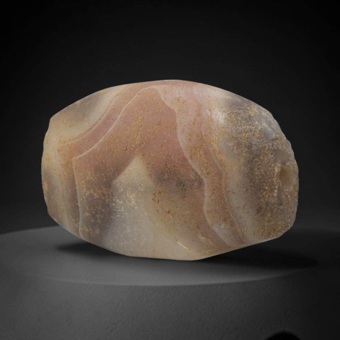 Ancient Agate Bead - Indus Valley Banded Amygdaloid Bead, 10XW: This bead is carved from translucent pale pink, grey, and creamy-white banded agate, shaped into a refined amygdaloid (almond-shaped) form with a precisely centered axial drill hole, characteristic of