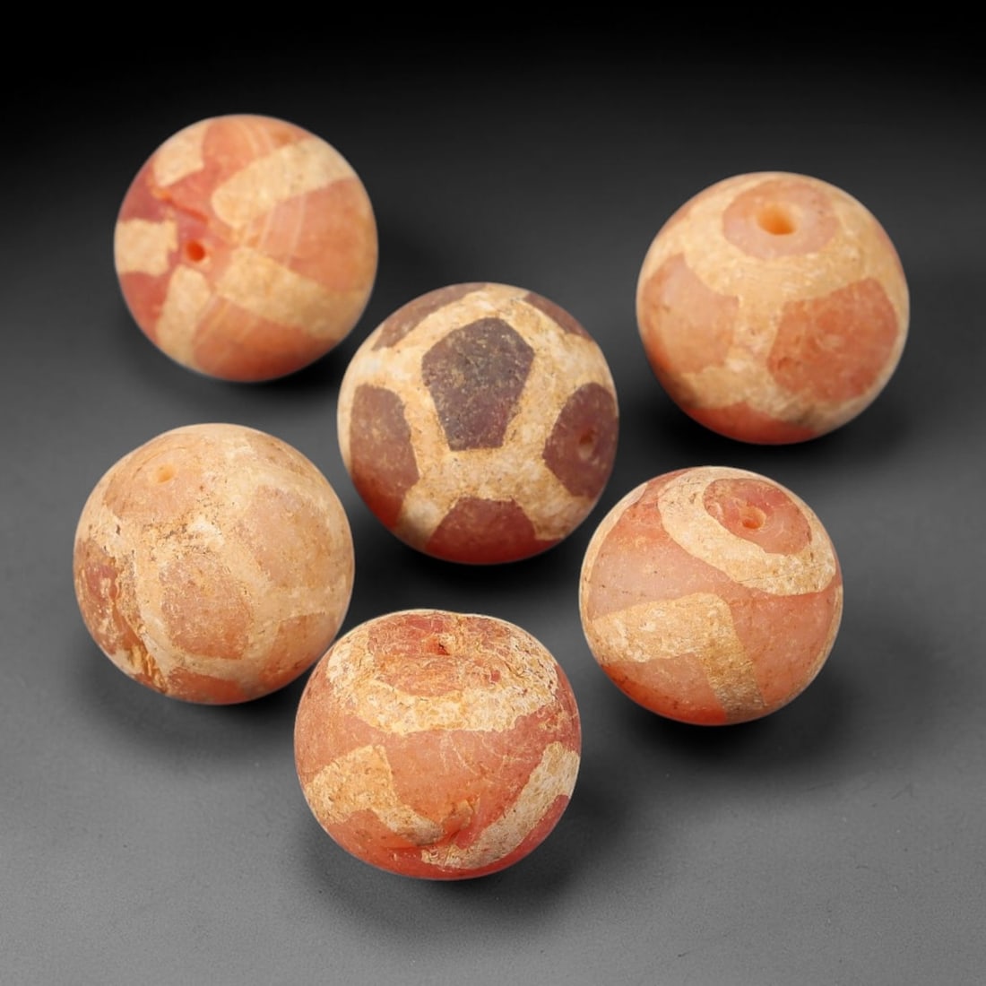 Ancient Carnelian Etched Beads - Gandhara Amulet Set, 34BE: Set of six spherical beads crafted from carnelian, each decorated with etched geometric motifs in a pale white pigment, characteristic of Gandharan decorative traditions. The beads retain a well-devel