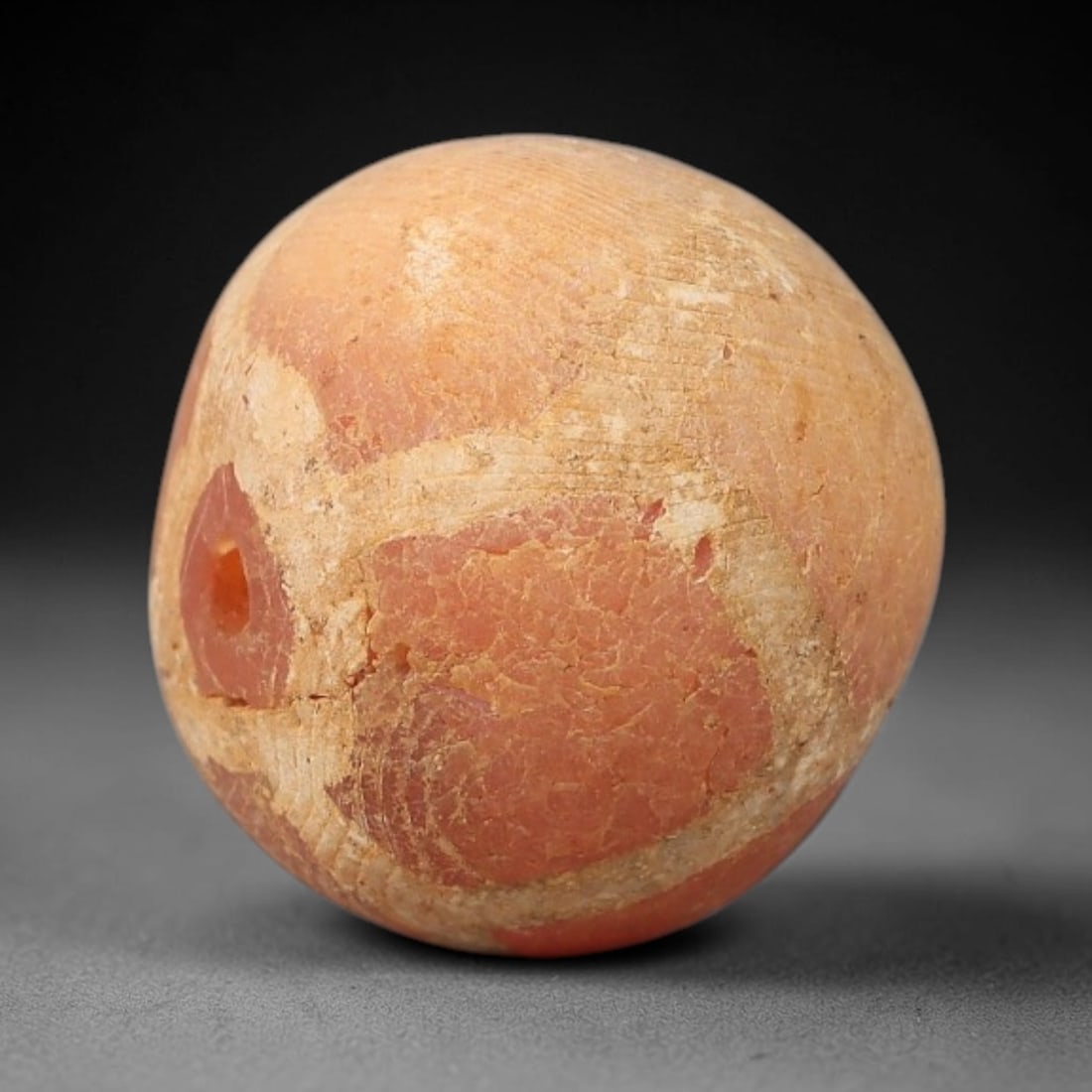 Ancient Carnelian Etched Bead - Gandhara Archaeological Find, 21BE: Carved from natural carnelian, the bead is spherical in form, featuring white etched geometric motifs across its surface. A lateral drilled suspension hole is present, consistent with Gandharan bead m