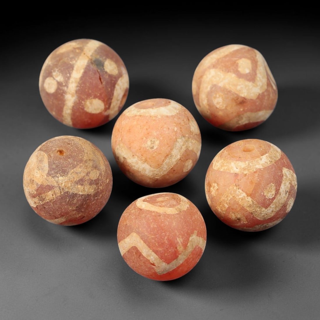 Ancient Gandhara Carnelian Etched Beads, Set of 6, 37BE: Crafted from natural carnelian, this set of six spherical beads features intricate etched geometric motifs, including angular, circular, and abstract patterns across their surfaces. Each bead retains