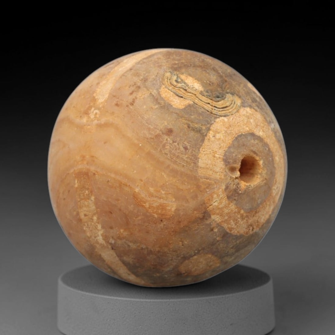 Ancient Carnelian Etched Bead - Gandhara Spherical Bead, 24XY: The bead is crafted from carnelian, a semi-precious chalcedony, with a spherical form and laterally drilled suspension hole. Its surface features an etched white pattern of circular and banded motifs,