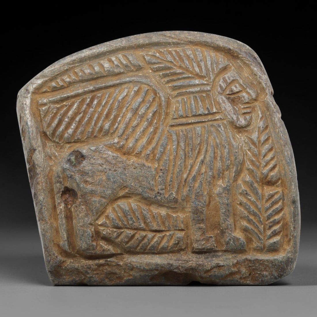 Ancient Stone Plaque Relief - Near Eastern Sphinx Figurine, 7ZY: Carved from a single piece of stone, this rounded rectangular relief plaque depicts a stylized sphinx, a composite mythological creature with a lion's body and human head, rendered in the linear, inci