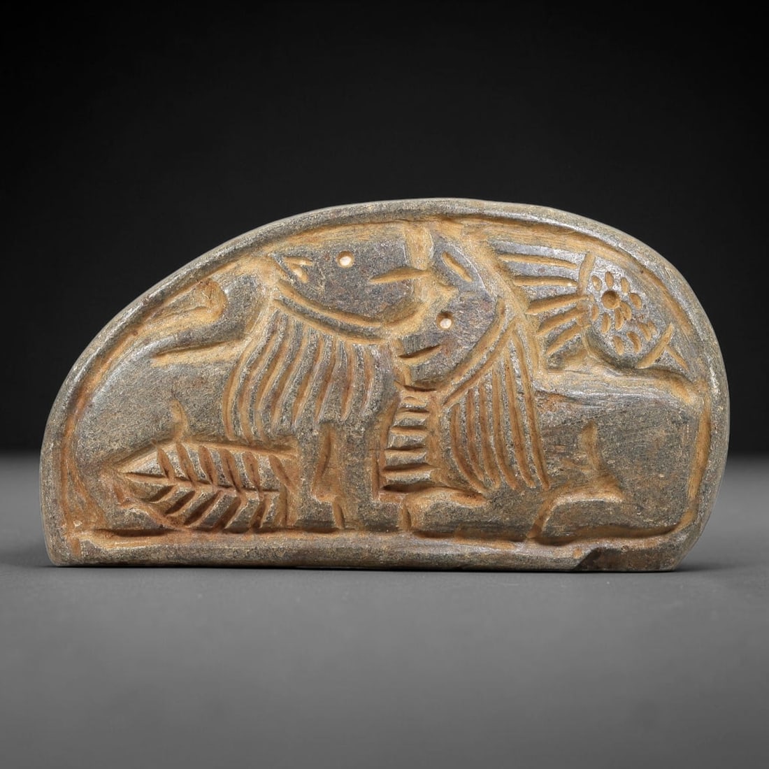 Ancient Stone Plaque Relief - Near Eastern Confronting Lions, 70BE: Carved from a single piece of stone, this semi-circular relief plaque depicts two confronting recumbent lions, rendered in the stylized, linear artistic tradition of the ancient Near East. The figures