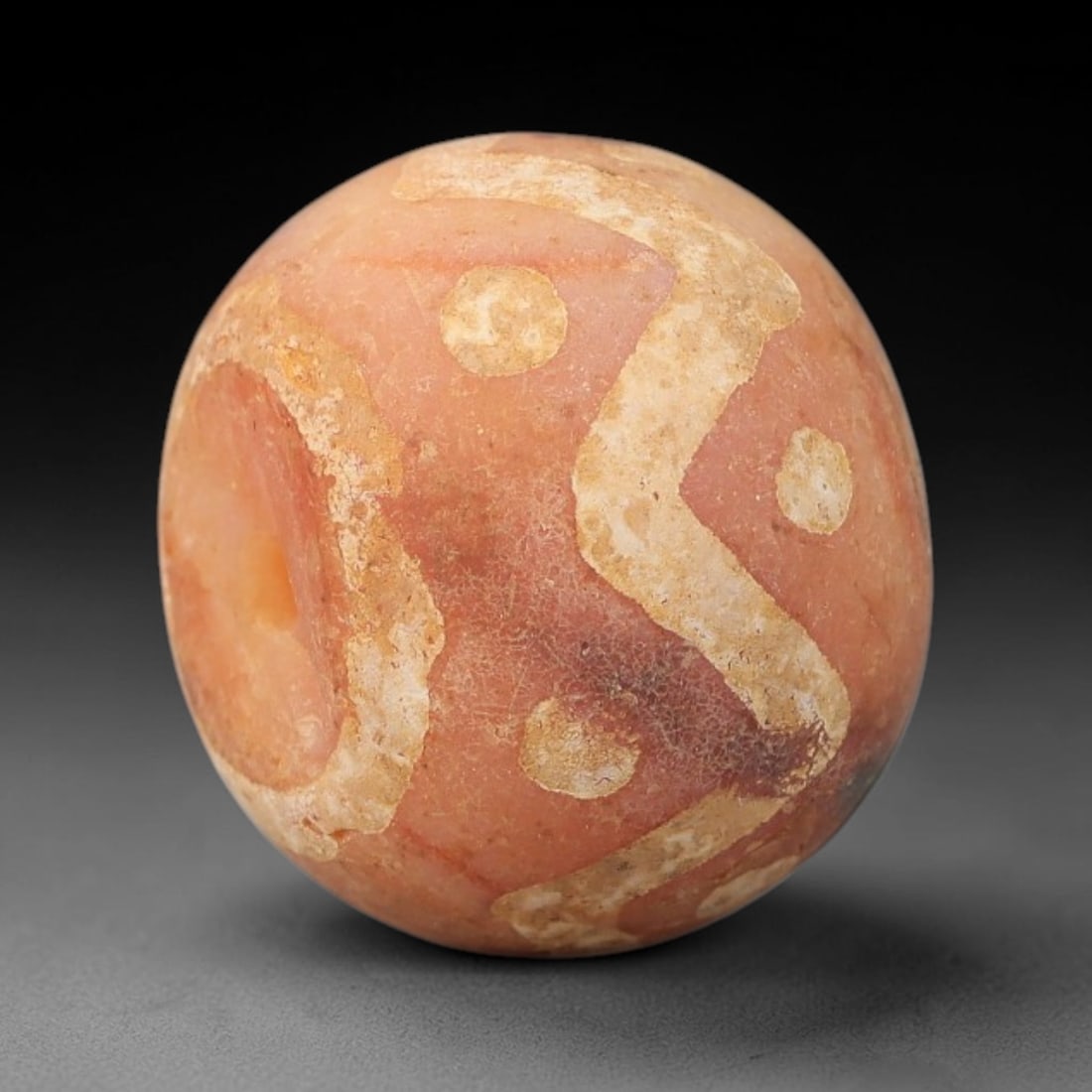 Ancient Carnelian Etched Bead - Gandhara Archaeological Find, 8BE: Carved from natural carnelian, the bead is spherical in form, adorned with white etched geometric motifs including circular and linear designs across its surface. A lateral drilled suspension hole is