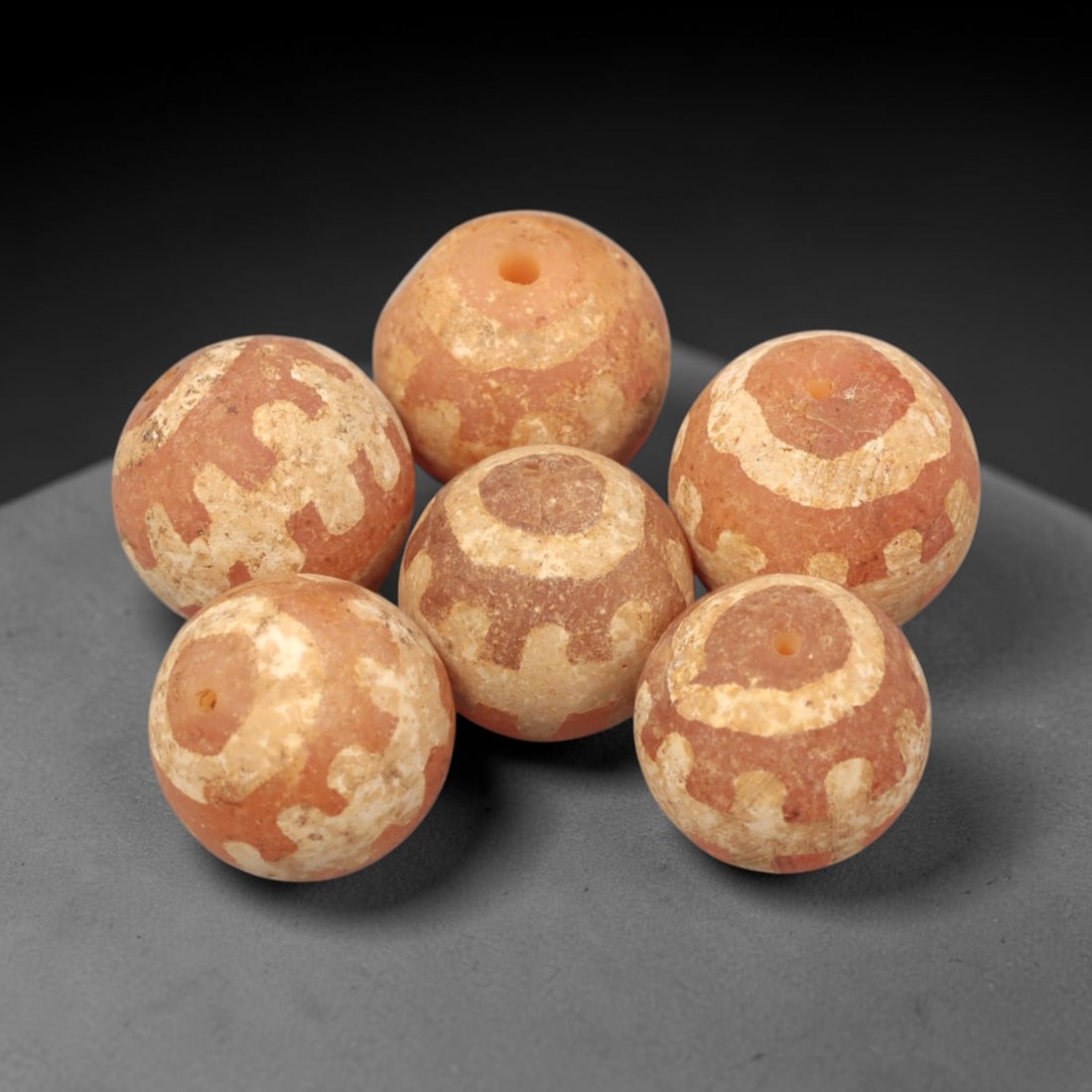 Ancient Carnelian Etched Beads - Gandhara Amulet Set, 76XY: Set of six spherical beads crafted from carnelian, each decorated with etched geometric motifs in a pale white pigment, characteristic of Gandharan decorative traditions. The beads retain a well-devel
