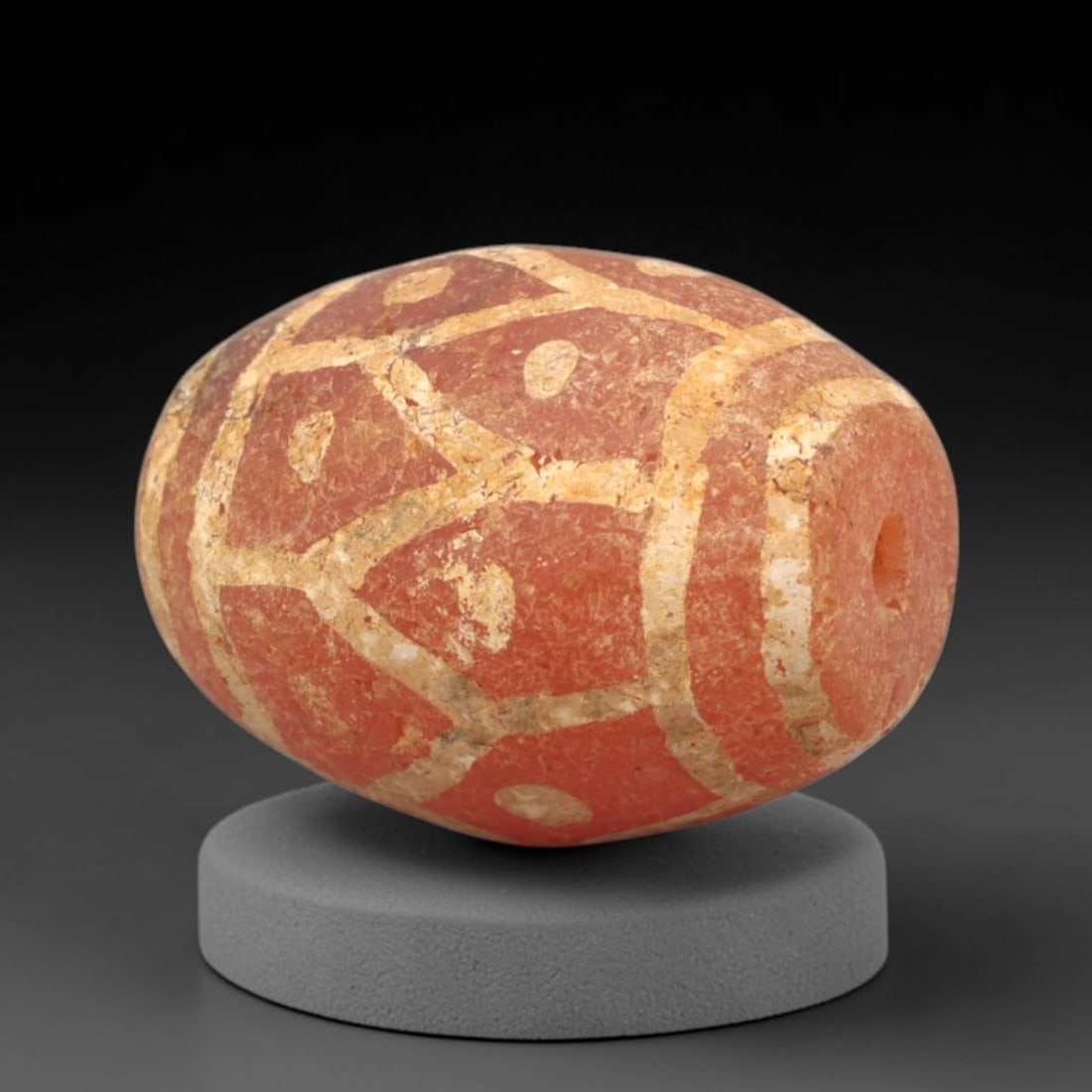 Ancient Carnelian Etched Bead - Gandhara Amulet, 50XY: Carved from carnelian, the bead is fashioned in an oval, barrel-shaped form with a lateral drilled suspension hole for wear. The surface is decorated with a geometric pattern of intersecting white-etc