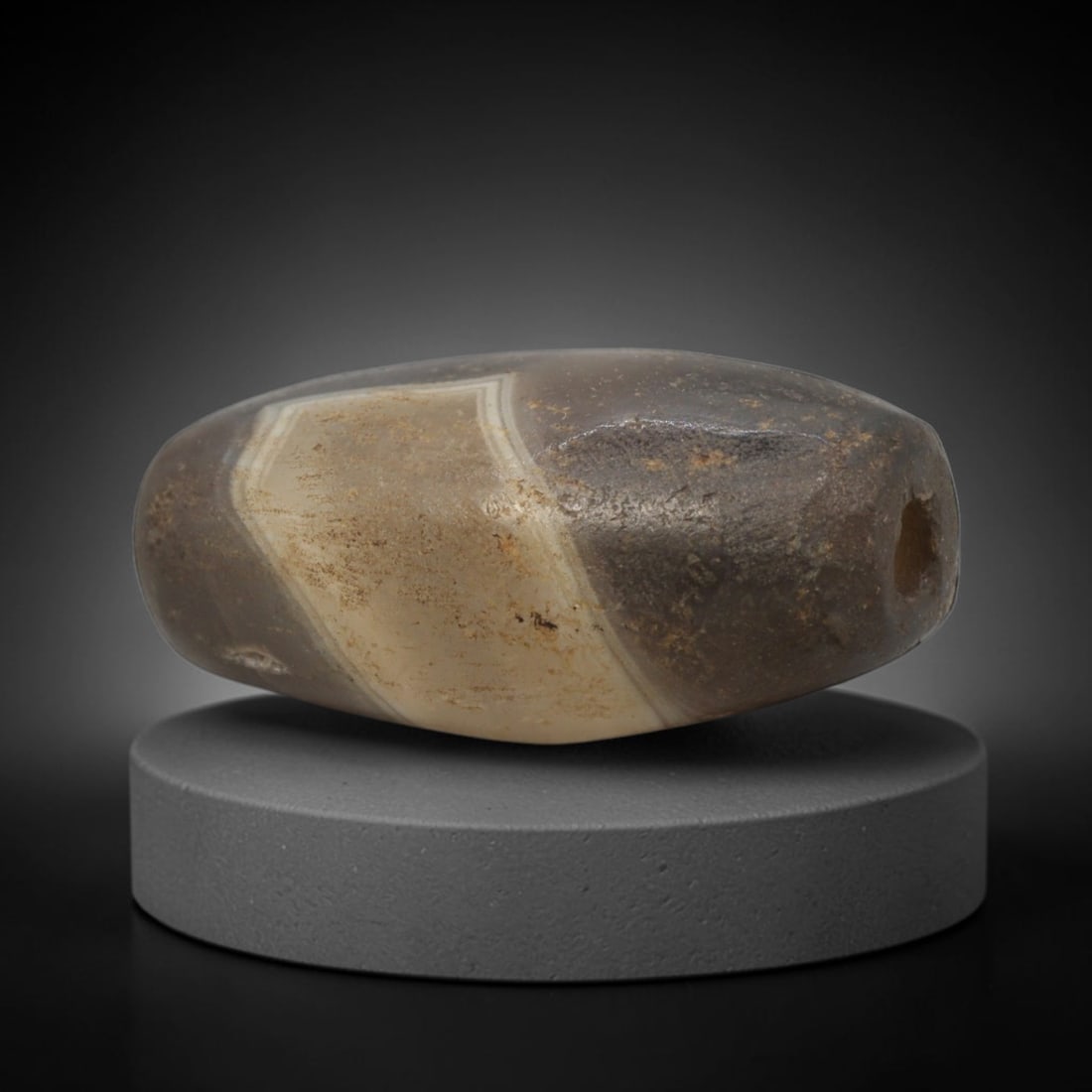 Ancient Agate Bead - Bactrian Banded Barrel Bead, 57XW: This bead is fashioned from translucent grey and creamy-white banded agate, shaped into a smooth, refined barrel form with a precisely centered axial drill hole, characteristic of ancient Bactrian lap
