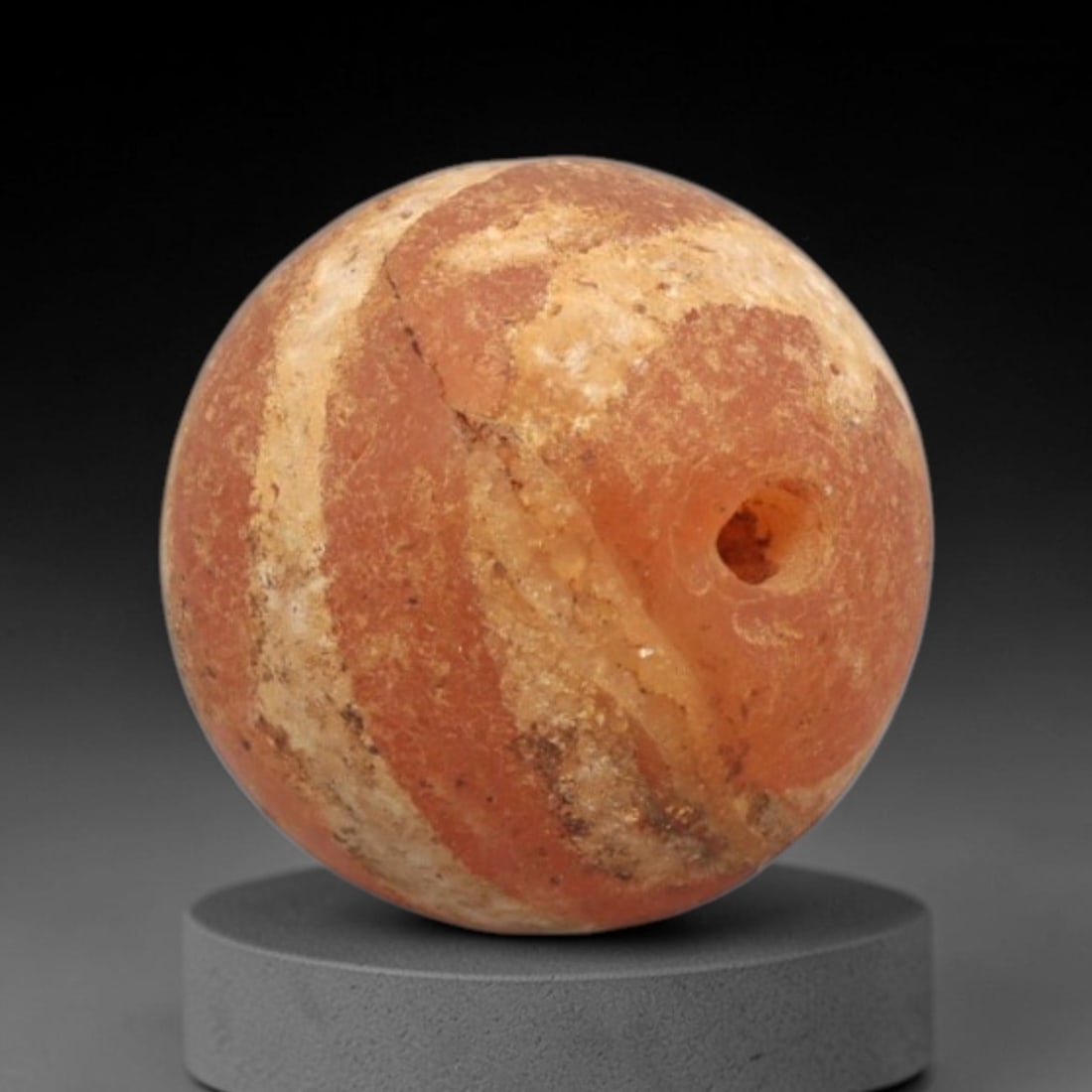 Ancient Carnelian Etched Bead - Gandhara Spherical Bead, 56XY: The bead is fashioned from carnelian, a semi-precious chalcedony, with a spherical form and a laterally drilled suspension hole for wear. Its surface is decorated with an etched white pattern of sweep