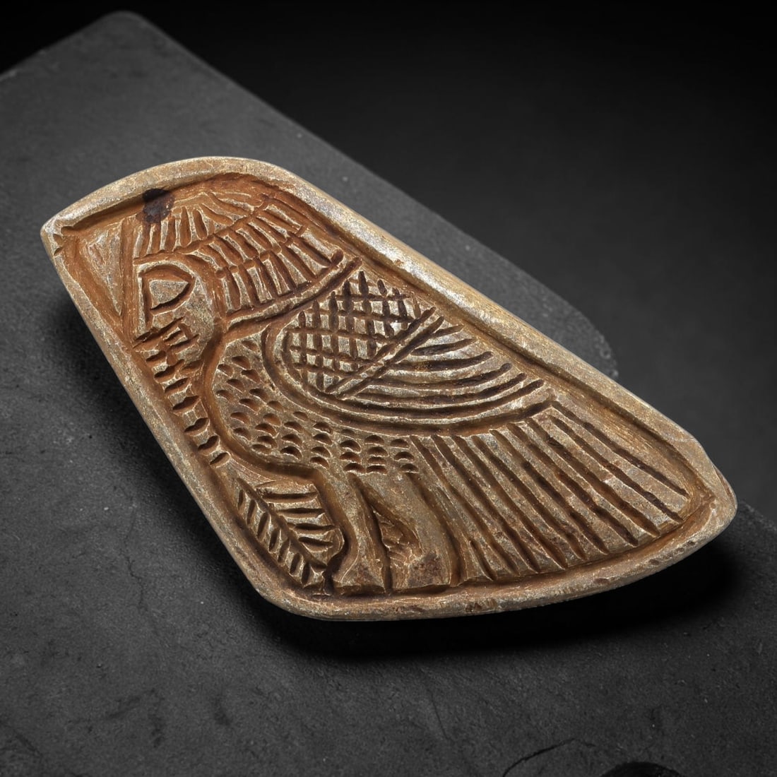 Ancient Stone Plaque Relief - Near Eastern Bird-Headed Deity, 74BE: Carved from a single piece of stone, this irregularly shaped relief plaque depicts a bird-headed anthropomorphic figure, rendered in the stylized, linear artistic tradition of the ancient Near East. T