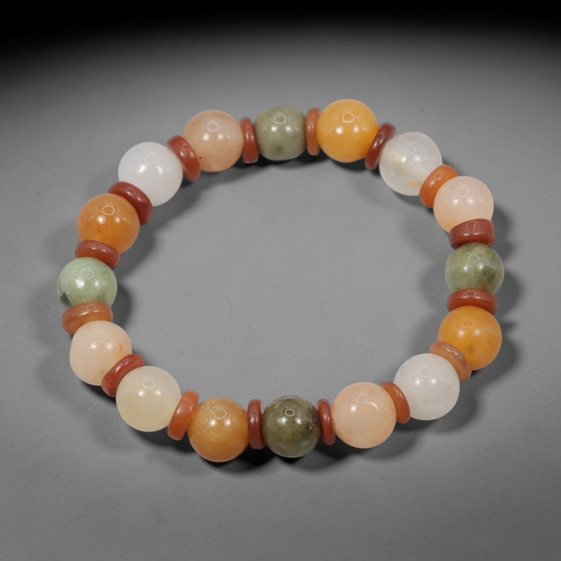 A Chinese Quartz and Jadeite Jade Bead Bracelet, 20th Century, 44ZK: Strung with spherical beads of quartz and jadeite jade, interspersed with small disc-shaped reddish spacers. The quartz beads exhibit natural color variations including white, peach, orange, and pale