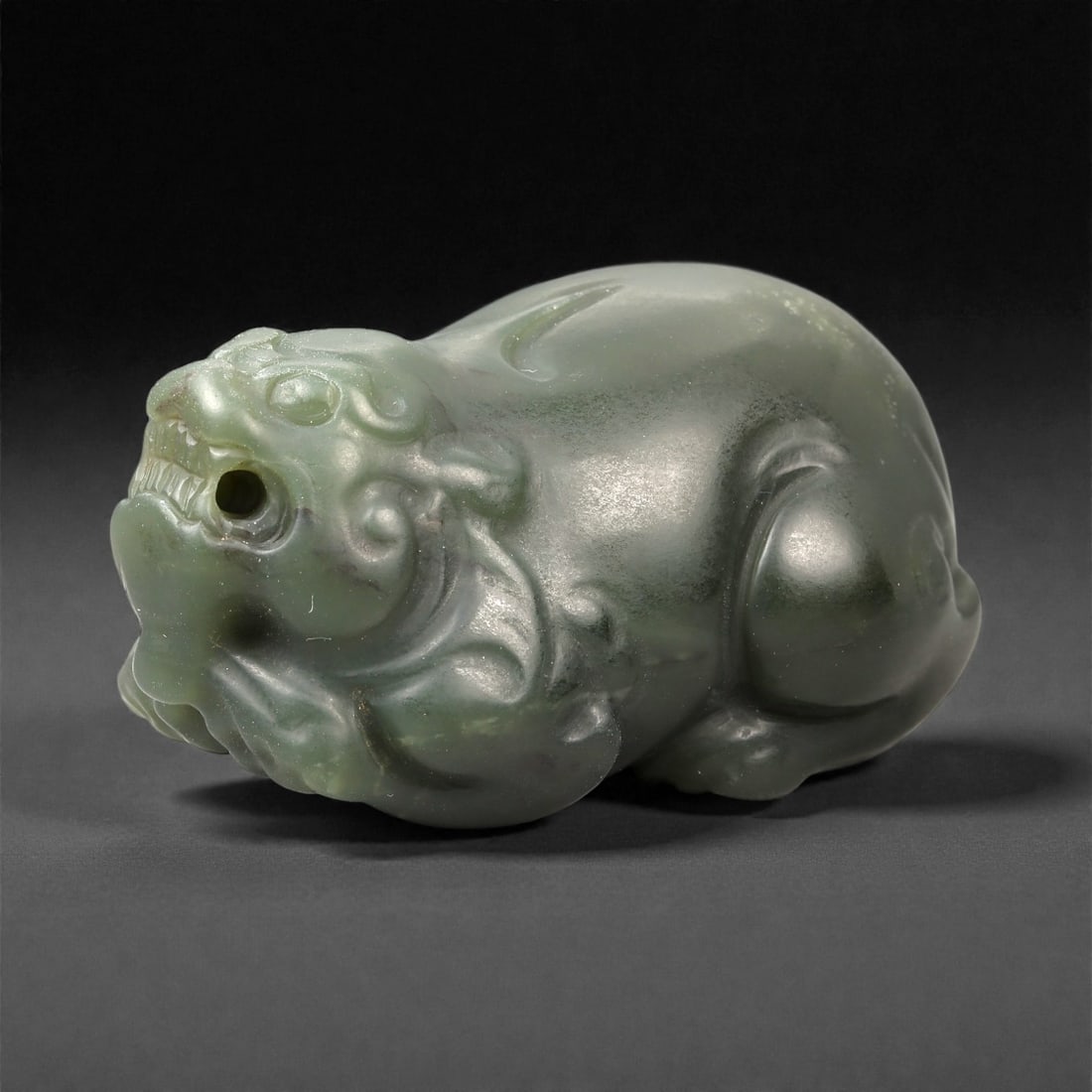 Chinese Jade Pixiu Beast - Carved Animal Figurine 5.2cm, 99ZC: Carved from pale green jade with soft translucency and subtle natural mottling, this sculptural figure represents a pixiu rendered in a compact recumbent posture. The carving is worked fully in the ro