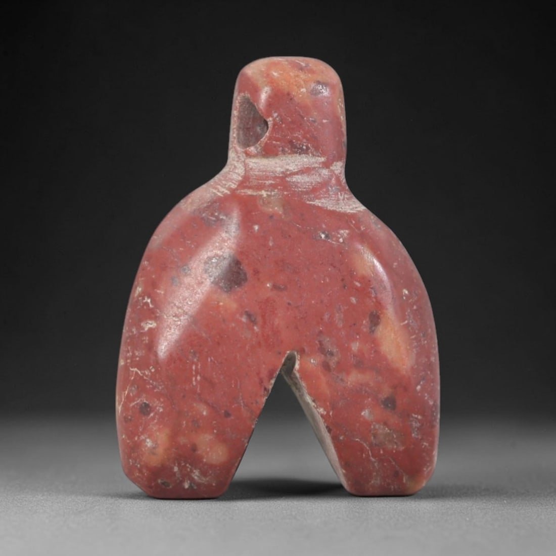 Ancient Stone Amulet - Near Eastern Ritual Figurine, 49AP: This artifact is carved from variegated red stone with a weathered, earthy patina and subtle mineral inclusions, exhibiting a stylized, symmetrical form consistent with ancient Near Eastern stoneworki