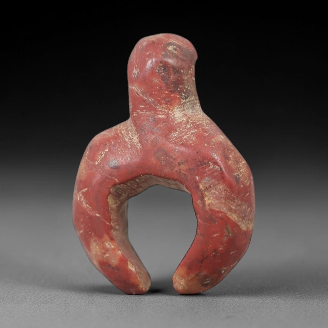 Ancient Stone Anthropomorphic Amulet - Near Eastern Ritual Figurine, 66AG: This amulet is carved from a single piece of mottled red stone, exhibiting a granular texture with pale ochre mineral veining and surface wear across its surface. The form is schematically rendered as