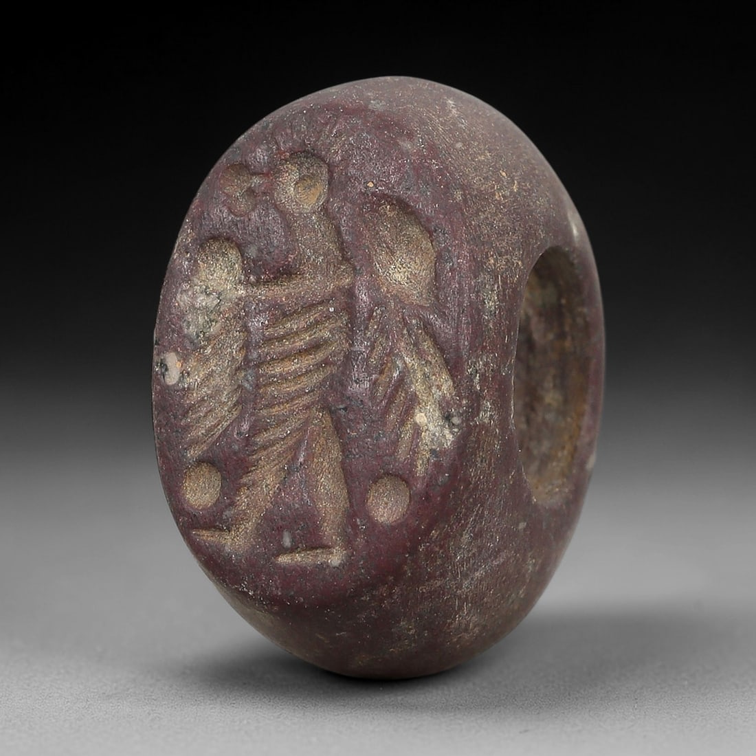 Ancient Stone Hemispherical Stamp Seal - Near Eastern Anthropomorphic Figure, 78AN: Carved from a dense, dark reddish-brown stone, this hemispherical stamp seal features a flat, circular face incised with a standing anthropomorphic figure. The figure is depicted with a headdress, a g