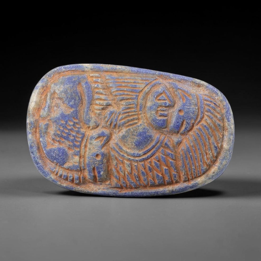 Near Eastern Lapis Lazuli Plaque - Tribal Figure & Animal Relief Carving, 95BF: Carved from rich lapis lazuli, this oval plaque features a 7x4.5cm (2.76x1.77in) relief composition centered on a stylized tribal figure, with incised linear details defining its form and geometric ac