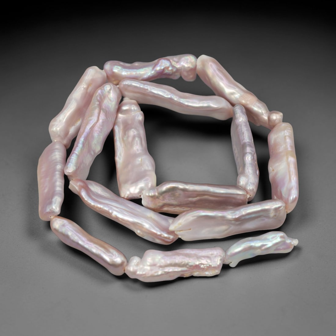 A Strand of Baroque Cultured Pearls, 20th Century, 89ZJ: Composed of elongated baroque cultured pearls with a soft pale pink body color and strong iridescent overtones, the strand is strung in a single continuous line. Each pearl exhibits a highly irregular