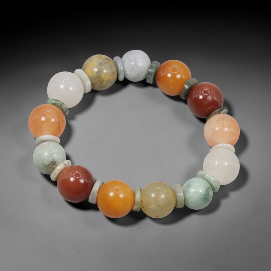A Chinese Quartz and Jadeite Jade Bead Bracelet, 20th Century, 39ZK: Strung with spherical beads of quartz and jadeite jade, separated by flat disc-shaped spacers. The quartz beads exhibit a spectrum of natural hues, including white, pale yellow, orange, peach, and red