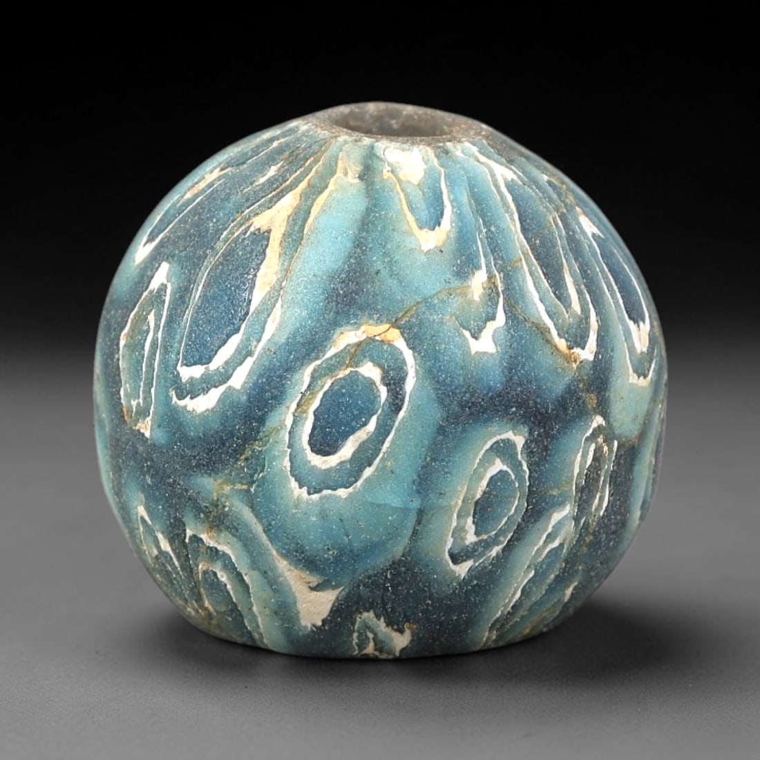 Ancient Glass Bead - Roman Marbled Mosaic Spherical Pendant, 34BG: A spherical ancient glass bead crafted in the marbled mosaic glass technique, with a layered teal-blue glass base overlaid with swirling white and cream-colored glass inclusions that form organic eye