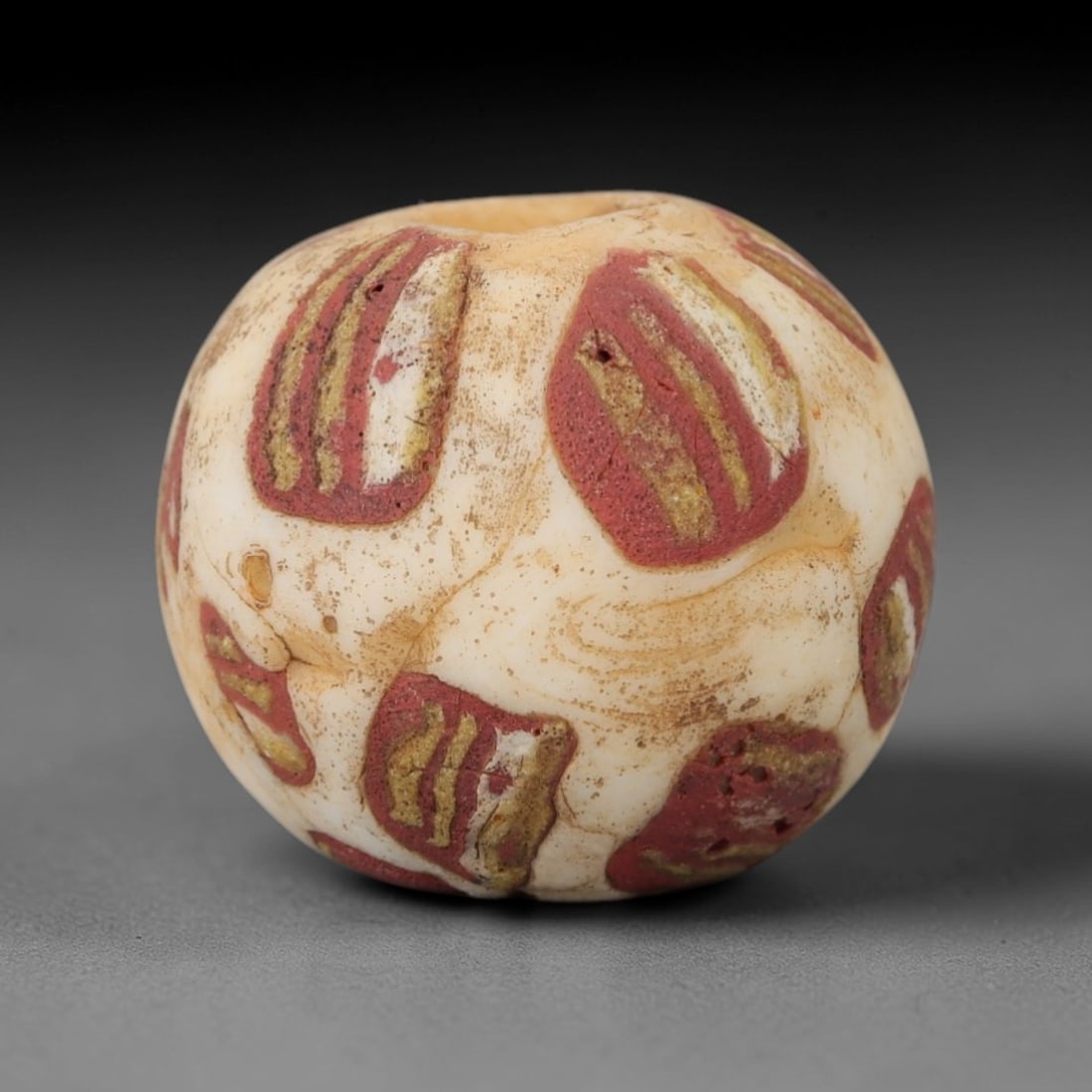 Ancient Glass Bead - Roman Bead, 58ZM: This ancient bead is crafted from opaque white glass, formed using the trailed and inlaid decorative techniques characteristic of Roman glassworking traditions. The spherical form features repeating r