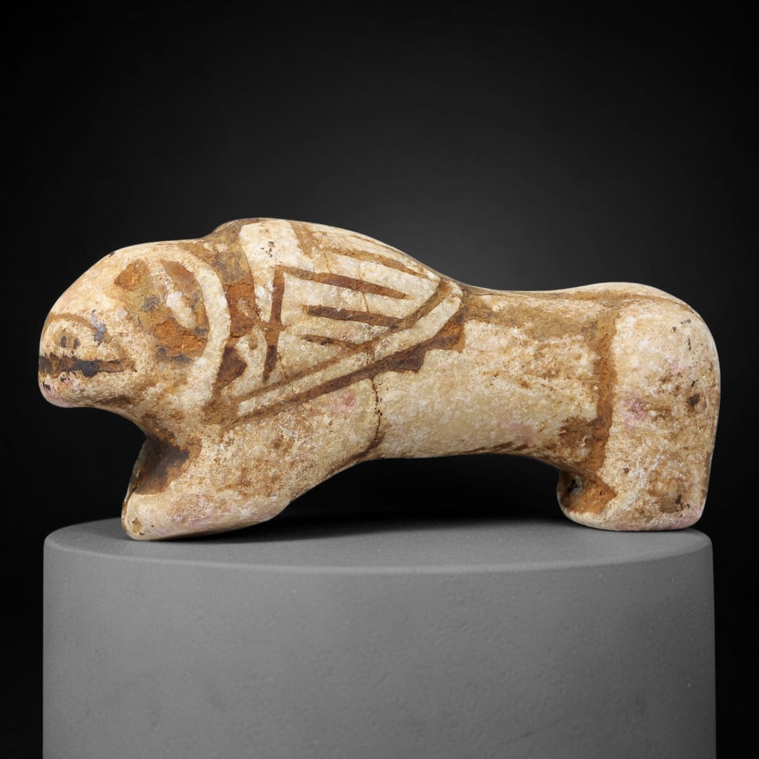 Ancient Stone Feline Figurine - Near Eastern Animal Amulet, 68BF: Carved from a light-colored stone with a naturally weathered surface, this figurine depicts a stylized feline in a crouched, forward-facing posture. The animal's form is rendered with simplified, robu