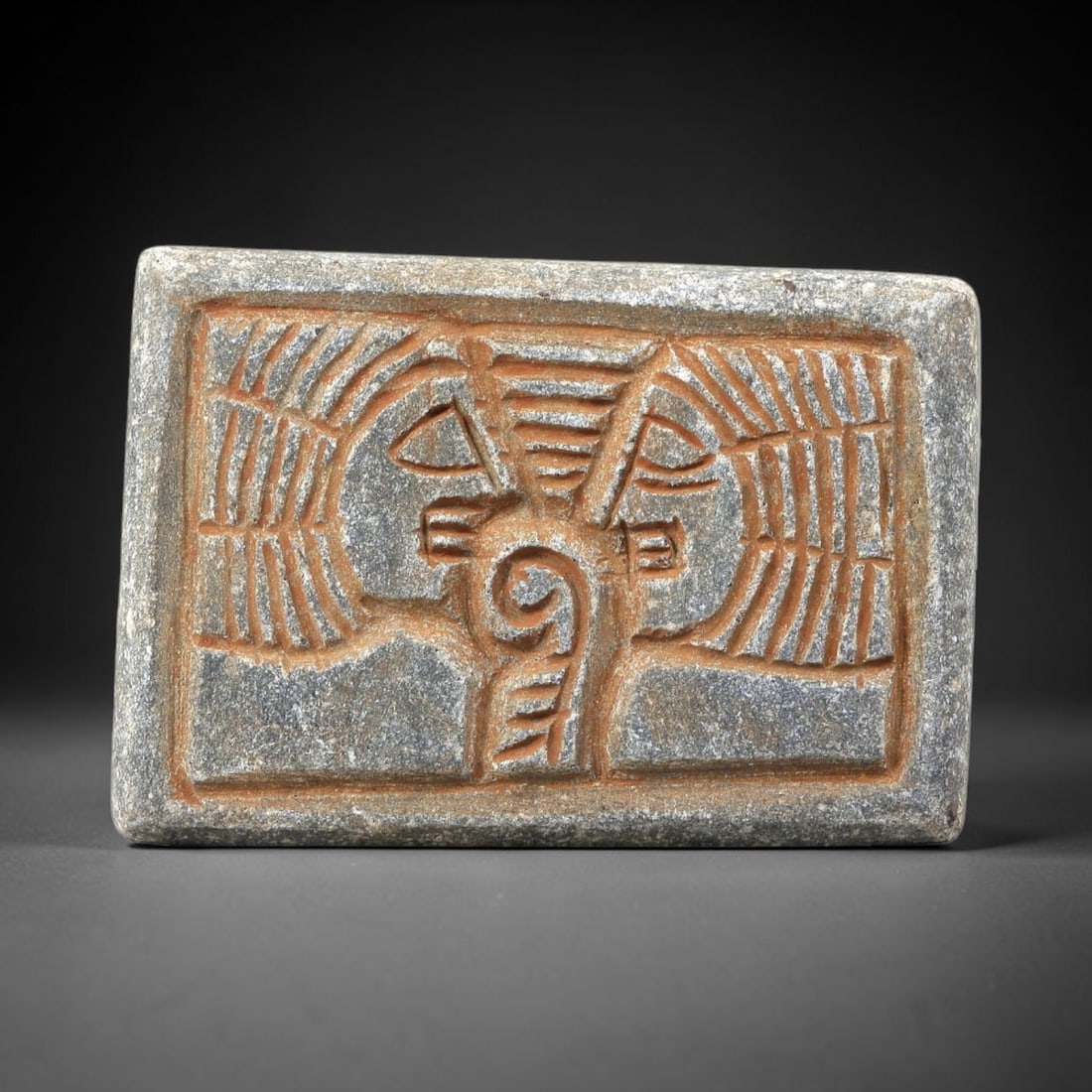 Near Eastern Schist Plaque - Tribal Art Dual Figure Relief, 70BG: Carved from schist, this rectangular plaque features a relief composition of two stylized anthropomorphic figures facing one another, flanking a central spiraled decorative motif, rendered with incise