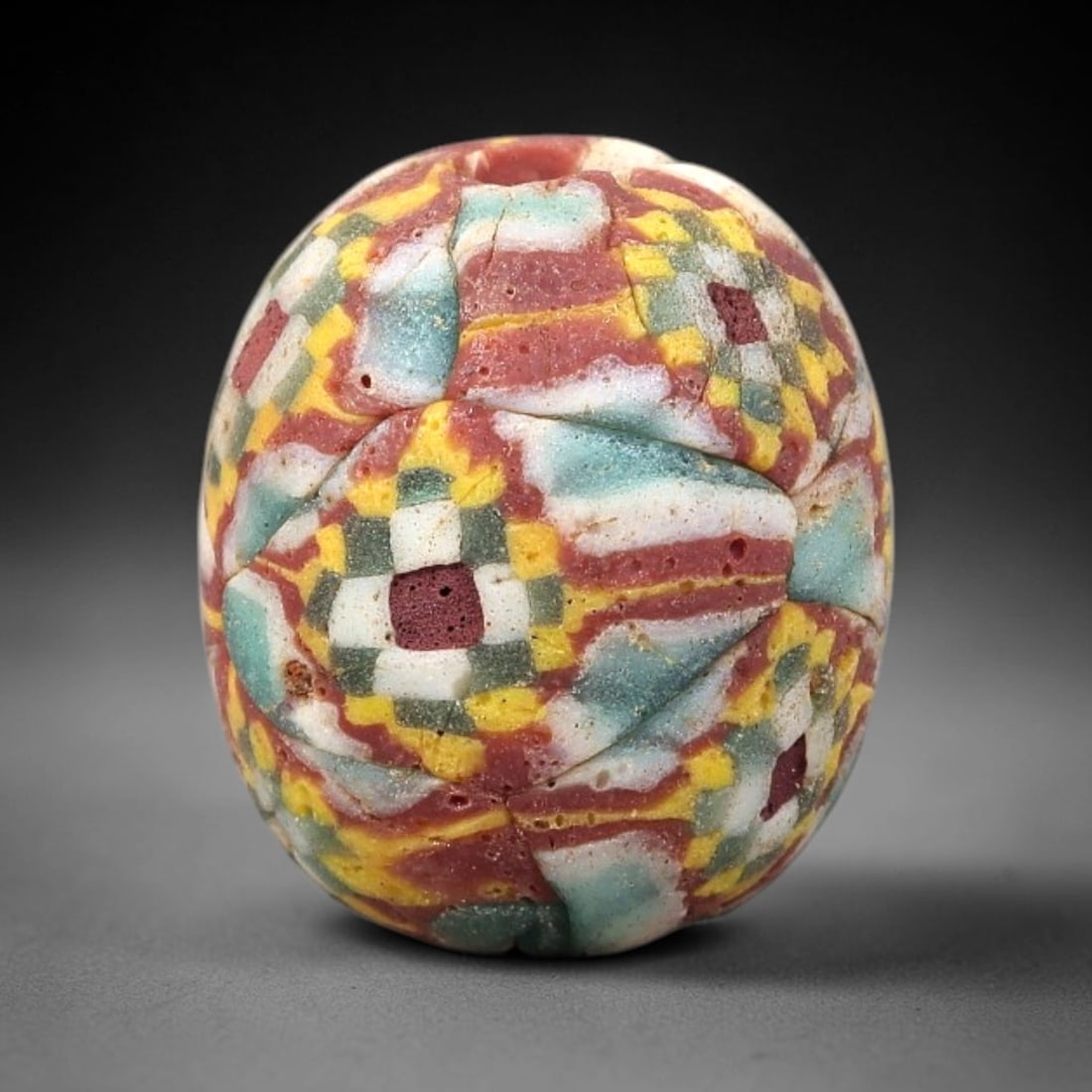 Ancient Glass Bead - Roman Mosaic Checkerboard Pendant, 22BG: A spherical ancient glass bead crafted in the mosaic glass technique, constructed from fused glass canes arranged in a geometric checkerboard pattern. The surface features interlocking square and rect