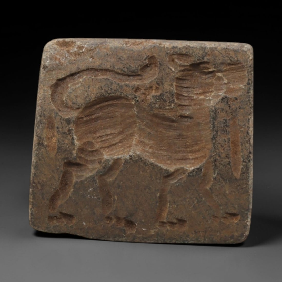 Ancient Steatite Amulet - Near Eastern Double Convex Stamp Seal, 16ZQ: Carved from steatite, this ancient Near Eastern double convex stamp seal features a stylized animal motif with linear detailing, typical of Near Eastern glyptic art. The compact form exhibits a smooth