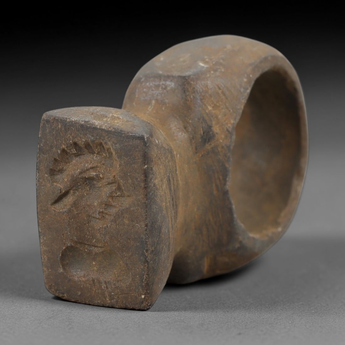 Ancient Steatite Achaemenid Ring - Intaglio Carving, 95AG: Carved from steatite stone, this ancient Achaemenid ring features a finely executed intaglio portrait on the bezel, a hallmark of Achaemenid glyptic art. The carving displays precise detail in the fac