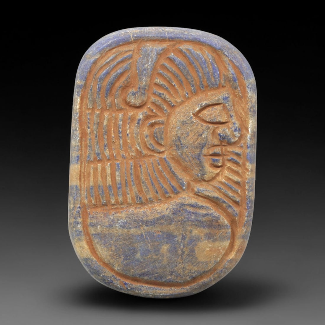 Near Eastern Lapis Lazuli Plaque - Tribal Art Male Figure Relief, 59ZY: Carved from lapis lazuli, this rounded rectangular plaque features a deeply incised relief profile of a stylized male figure, rendered in a geometric tribal idiom. The figure is depicted with detailed