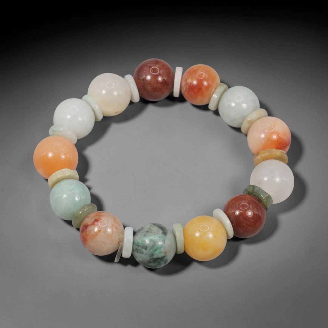 A Chinese Jadeite Jade Bead Bracelet, 20th Century, 89FS: Composed of spherical beads of multicolored jadeite jade, including pale celadon, orange, red, yellow, and white, with natural veining and minor internal inclusions, the bracelet is strung in a contin