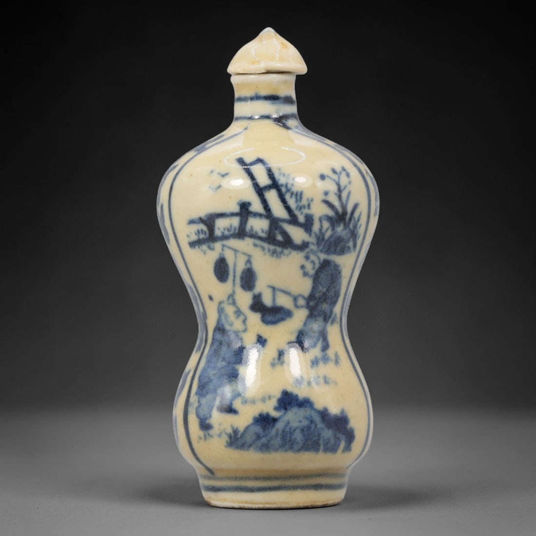 A Chinese Porcelain Double-Gourd Snuff Bottle, 20th Century, 54BE: Crafted from porcelain with a pale cream glaze and decorated in underglaze blue, the snuff bottle is formed in a double-gourd shape, with a narrow upper bulb, a wider lower bulb, and a short neck fitt