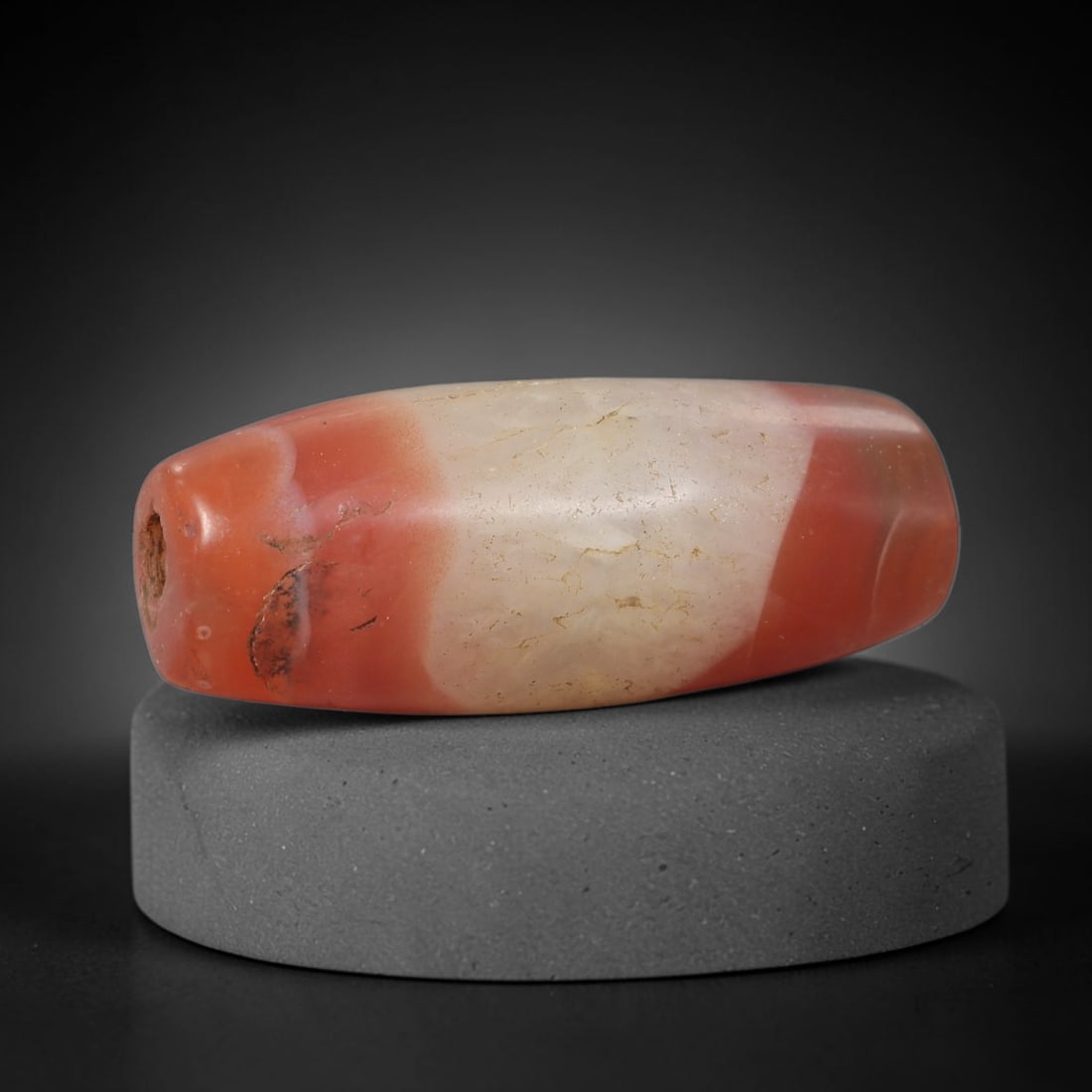 Ancient Agate Bead - Tibetan Amulet, 40BD: This artifact is crafted from striking banded agate, showcasing bold blocks of vivid carnelian red and creamy milky white across its smooth elongated barrel form, shaped through skilled ancient lapida