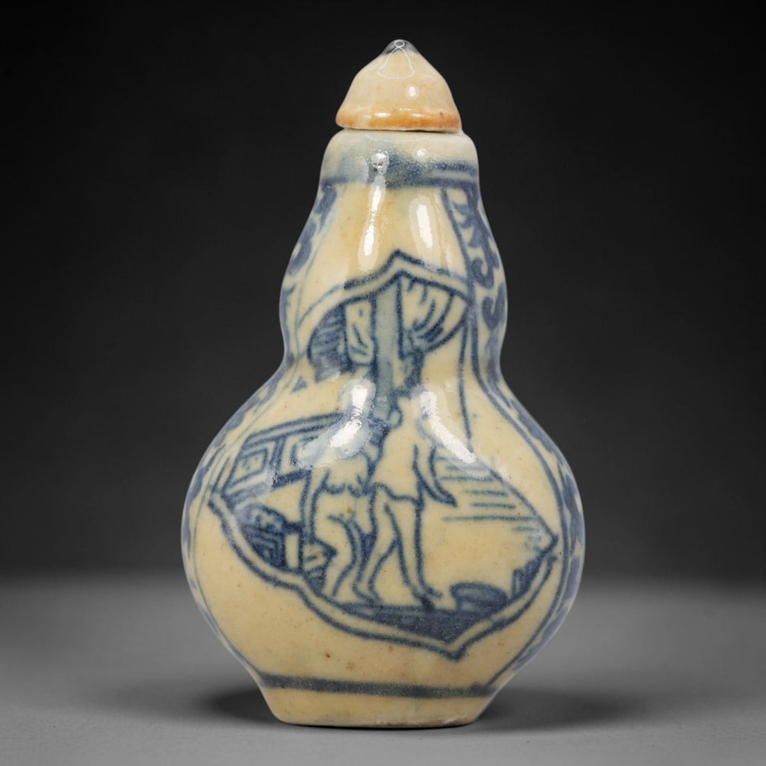A Chinese Porcelain Double-Gourd Snuff Bottle, 20th Century, 1YD: Crafted from porcelain with a pale cream glaze and decorated in underglaze blue, the snuff bottle is formed in a double-gourd shape, with a narrow upper bulb, a wider lower bulb, and a short neck fitt