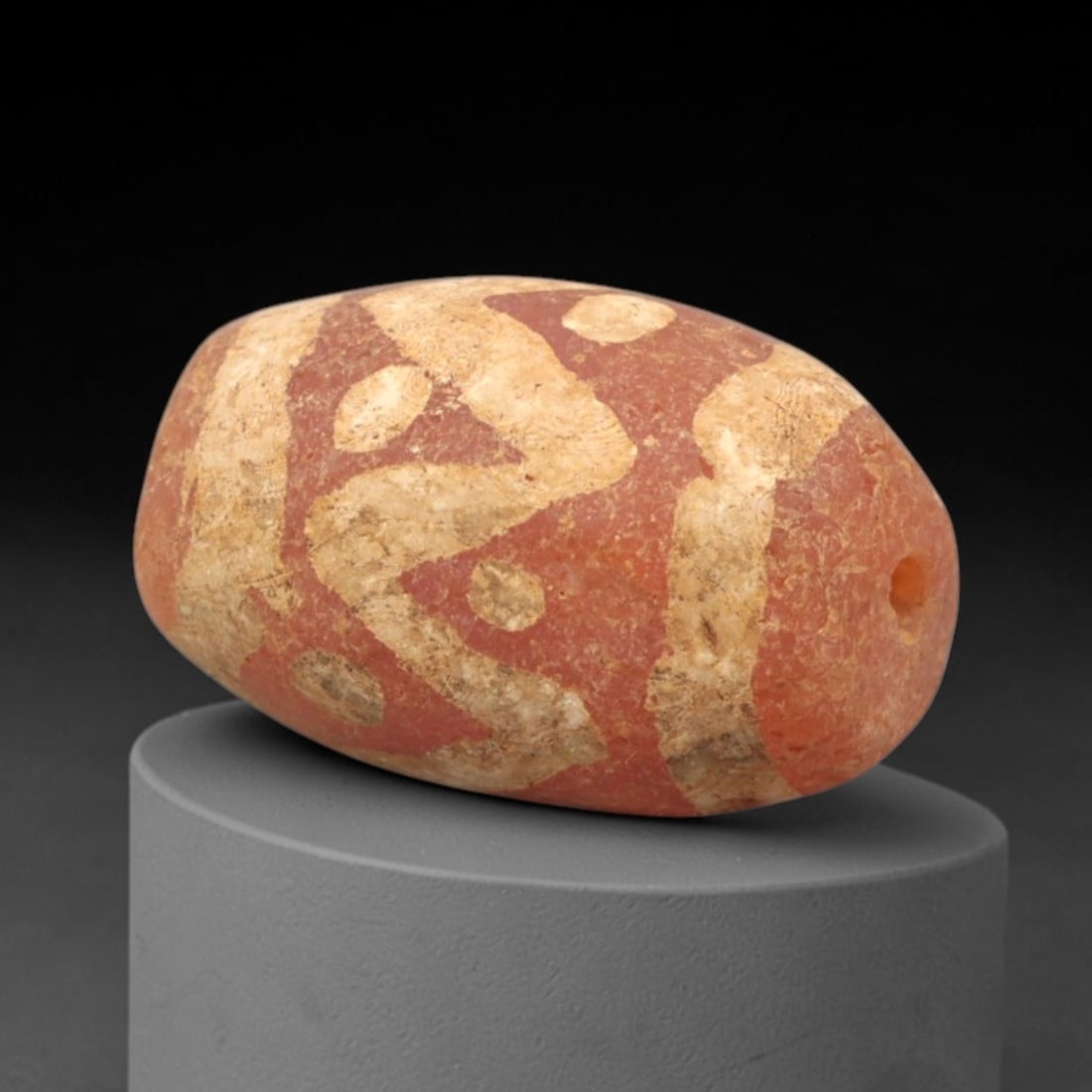 Ancient Carnelian Etched Bead - Gandhara Amulet, 46XY: Carved from carnelian, the bead is fashioned in an elongated barrel form with a lateral drilled suspension hole for wear. The surface is decorated with a dynamic white-etched pattern of curvilinear ba
