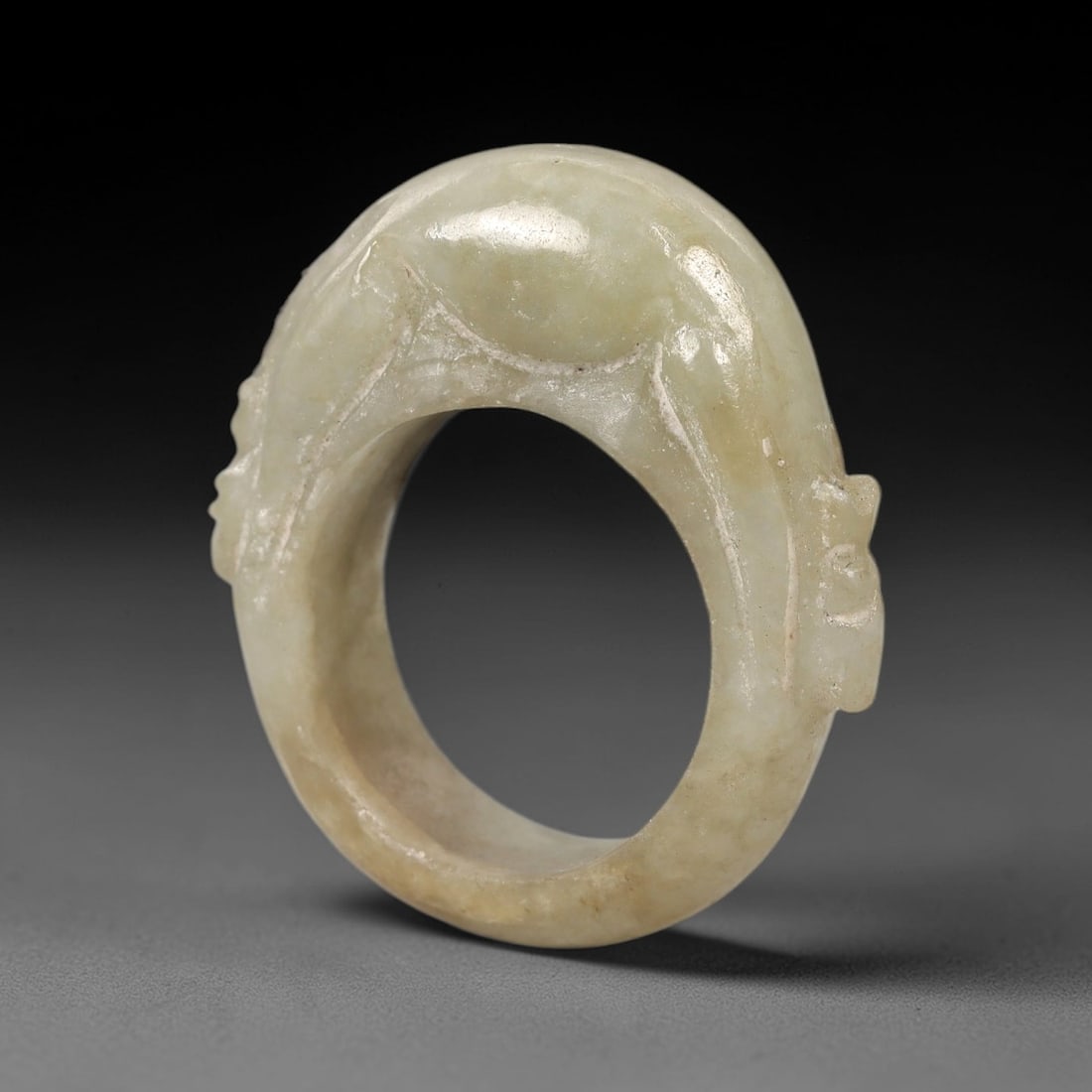 A Chinese Jadeite Jade Mouse-Form Ring, Qing Dynasty, 66FS: Carved from pale greenish-white jadeite jade with natural brownish inclusions and subtle internal veining, the object is formed as a circular ring with a raised, carved mouse integrated into the outer