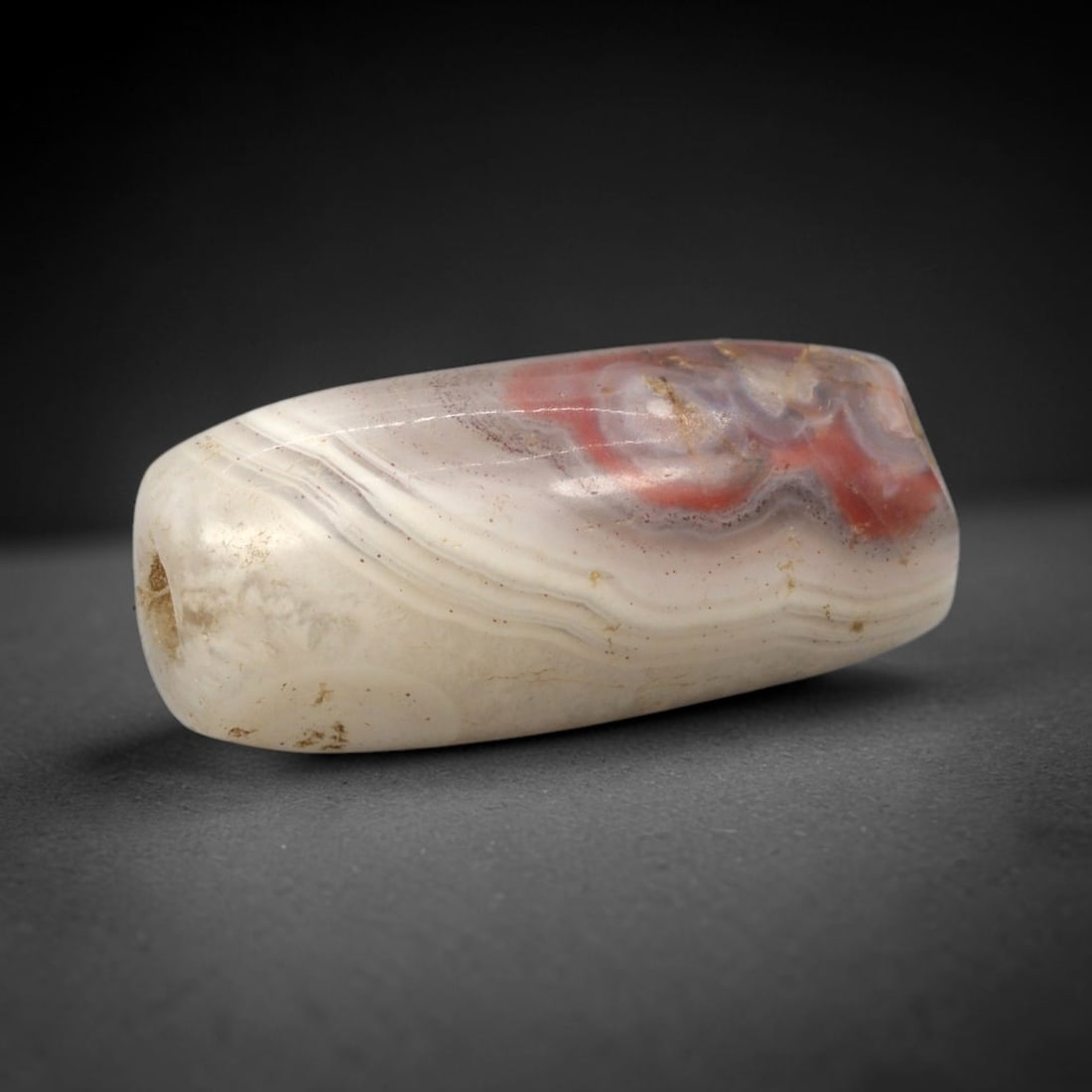 Ancient Agate Bead - Bactrian Tubular Bead, 99XW: This bead is fashioned from banded agate with distinct layers of creamy-white, pale grey, and subtle rose-hued mineralization, shaped into a refined tubular form with a precisely centered axial drill