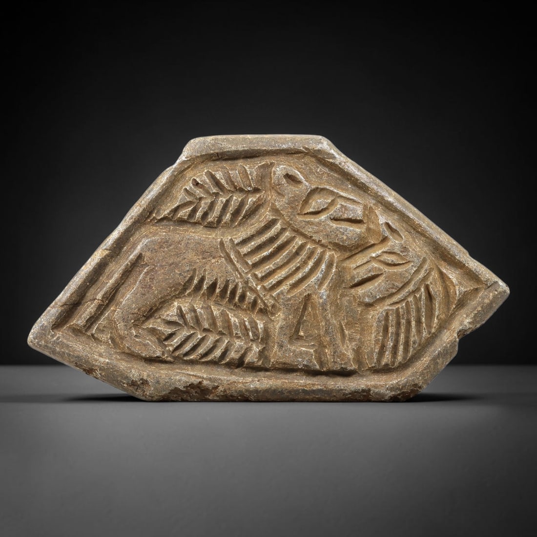 Ancient Stone Plaque Relief - Near Eastern Winged Beast, 65BE: Carved from a single piece of stone, this irregularly shaped relief plaque features a dynamic depiction of a winged mythological beast, likely a griffin, a composite creature with the body of a lion a