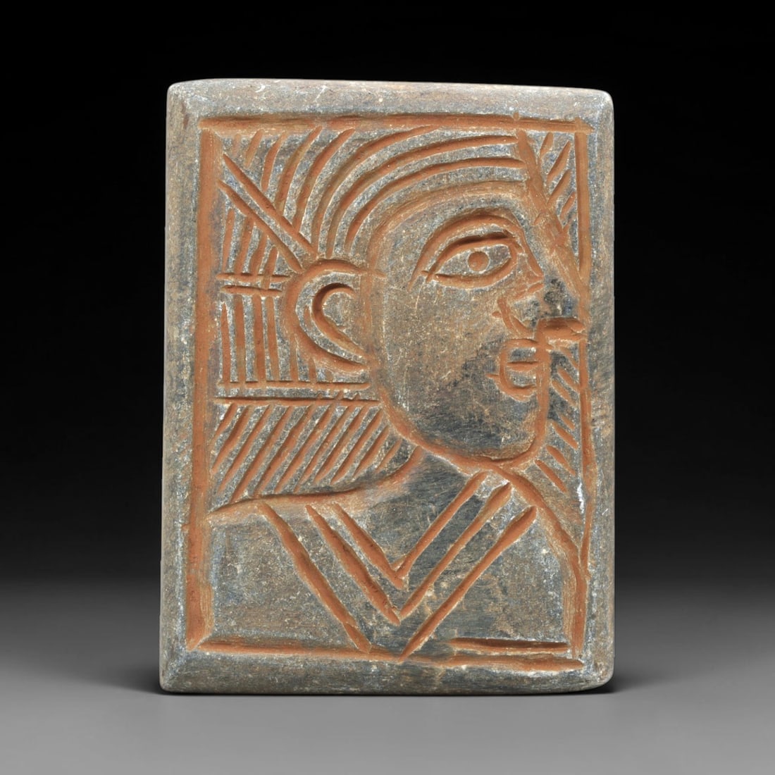 Near Eastern Schist Plaque - Tribal Art Figure Head Relief, 90ZY: Carved from natural schist stone, this Near Eastern tribal art plaque relief features a hand-carved depiction of a stylized human figure head in profile, executed with incised linear and geometric tec