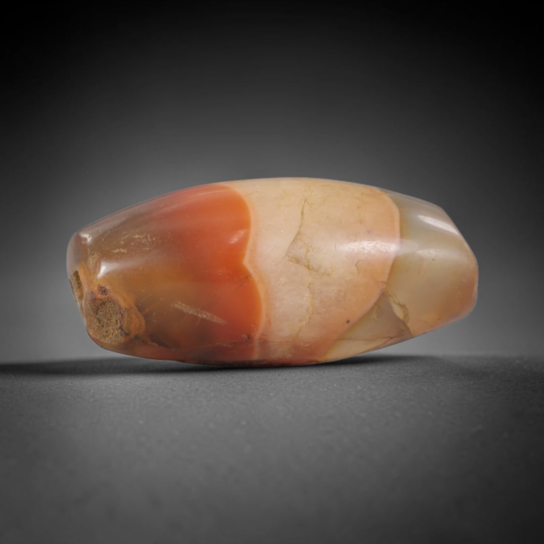 Ancient Agate Bead - Silk Road Bicone Carving, 89AS: This artifact is crafted from banded agate, featuring distinct color zoning of rich reddish-orange and pale cream tones with subtle translucency across the polished surface. The bead is formed in an e