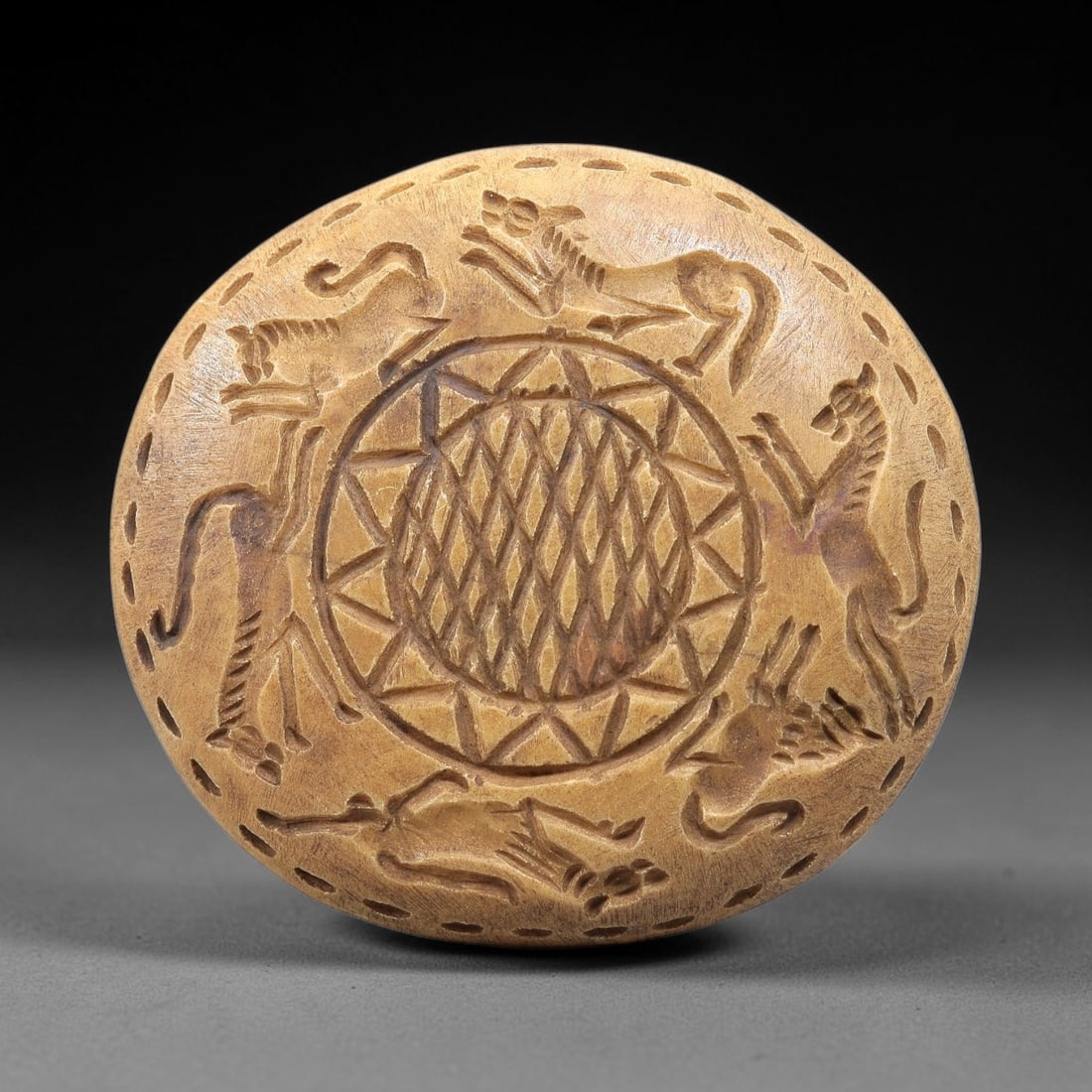 Near Eastern Steatite Disc - Tribal Art Animal Relief, 99BE: Carved from steatite, this circular disc features a deeply incised relief composition centered on a geometric lattice motif within a sunburst border, surrounded by six stylized animal figures rendered