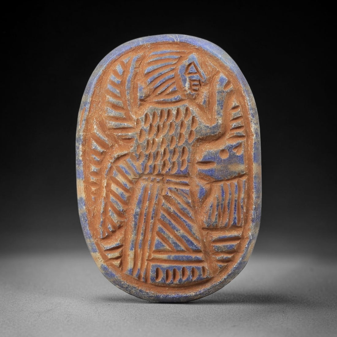 Near Eastern Lapis Lazuli Plaque - Tribal Art Figure Relief, 77BF: Carved from lapis lazuli, this oval plaque features a detailed relief depiction of a stylized human figure in the expressive, linear style characteristic of Near Eastern tribal art. The figure is rend